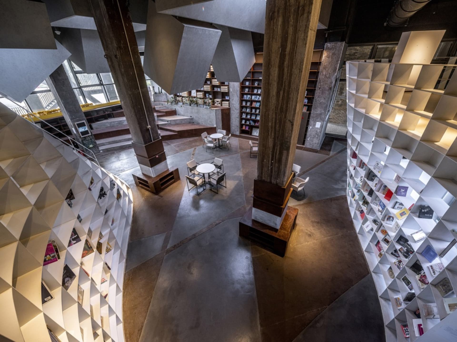 A modern library interior with concrete finishes and geometric bookshelves.