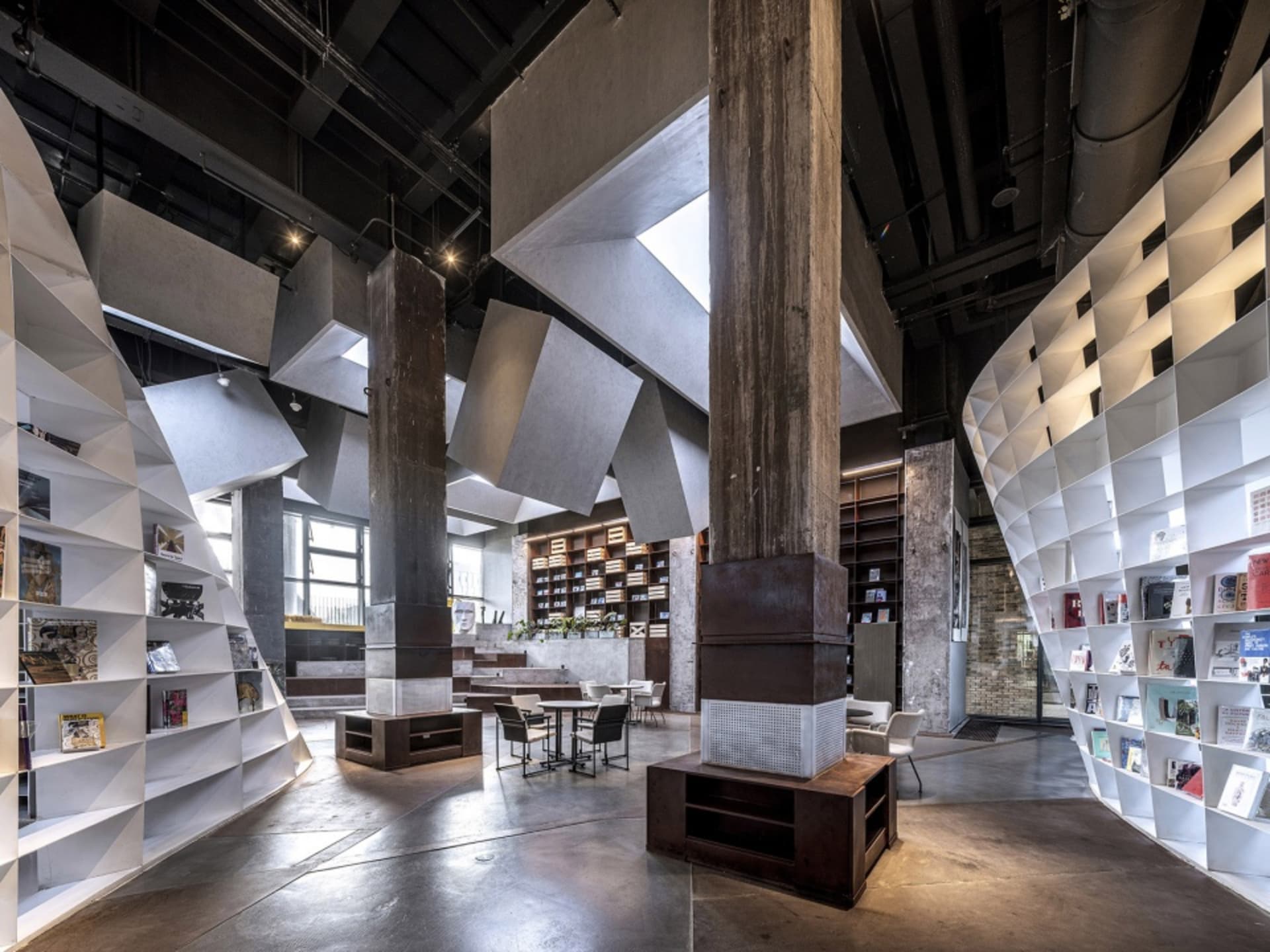 寬敞的工業風圖書館,混凝土牆面與地板,搭配現代家具,呈現開放通透的設計。