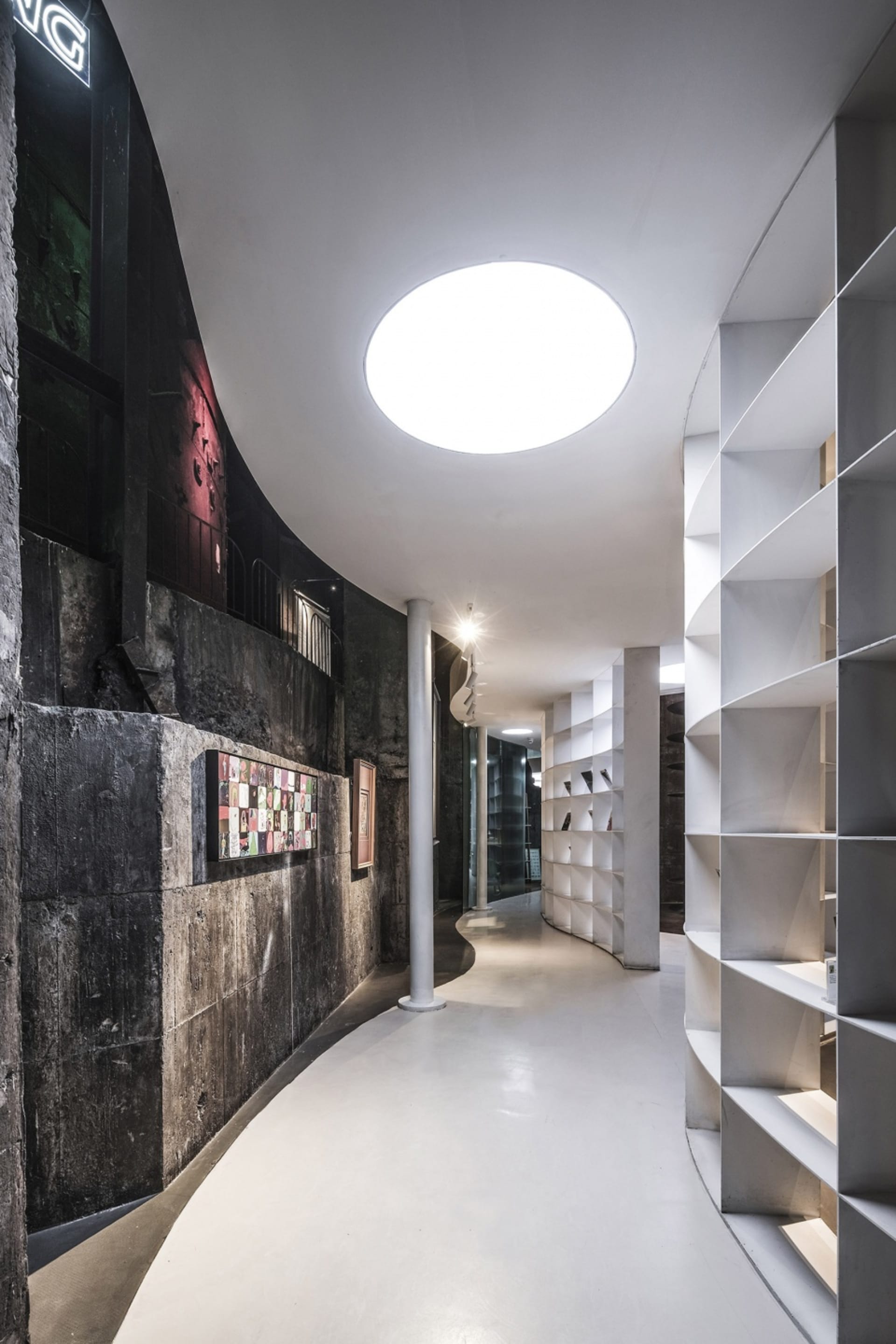 An image of a modern concrete closet with a curved wall and a large circular skylight.