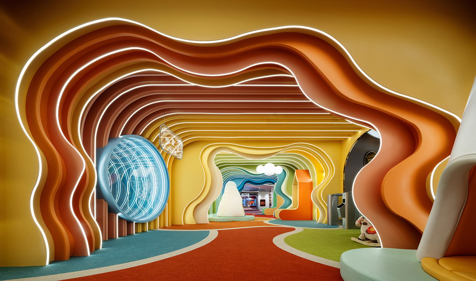 A brightly colored, modern playground with curved walls and a colorful indoor slide.