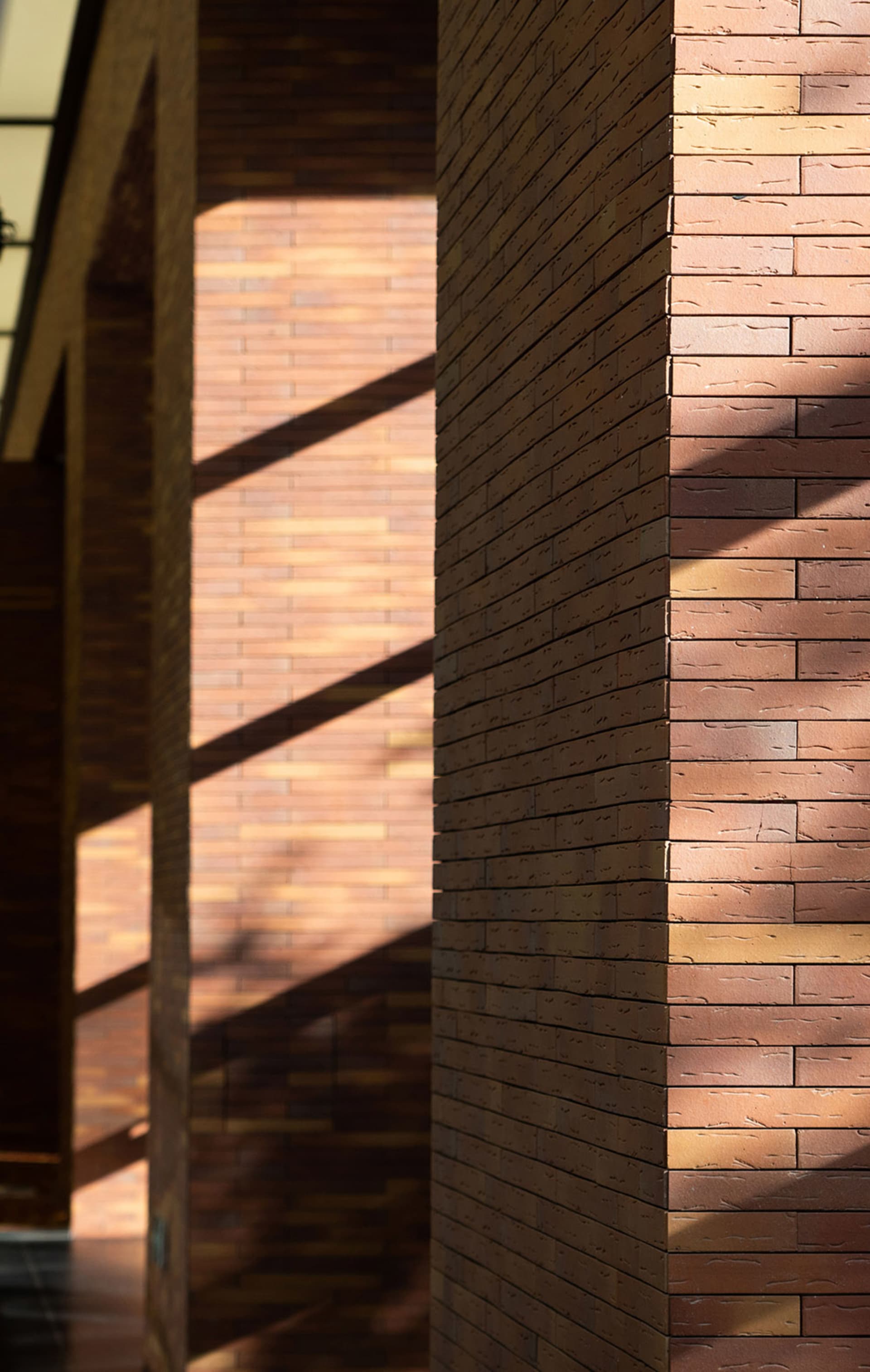 Modern interior design featuring a brick column with sunlight casting shadows.