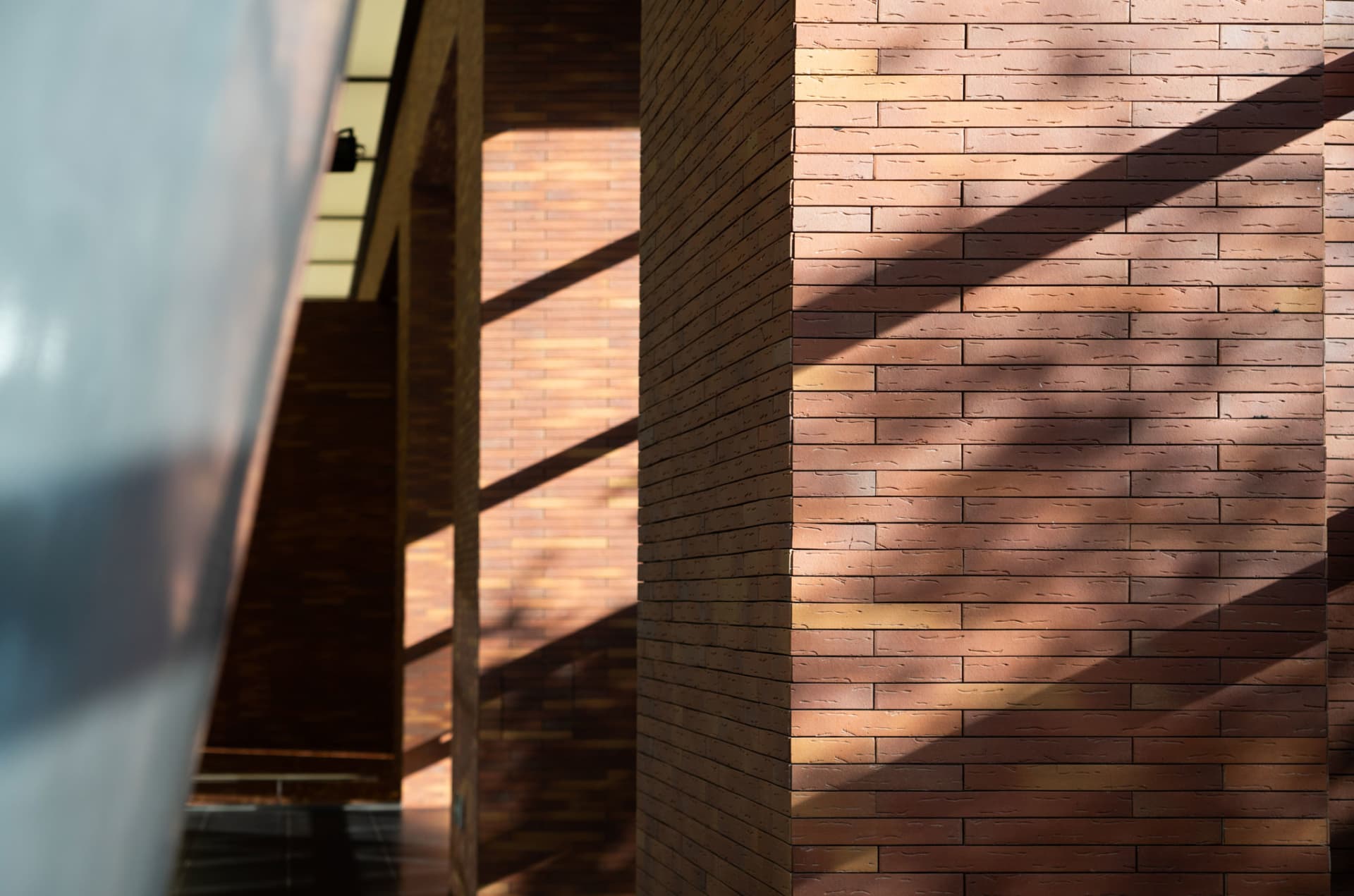 A close-up of modern brick walls with sunlight casting shadows, showcasing contemporary architectural design.