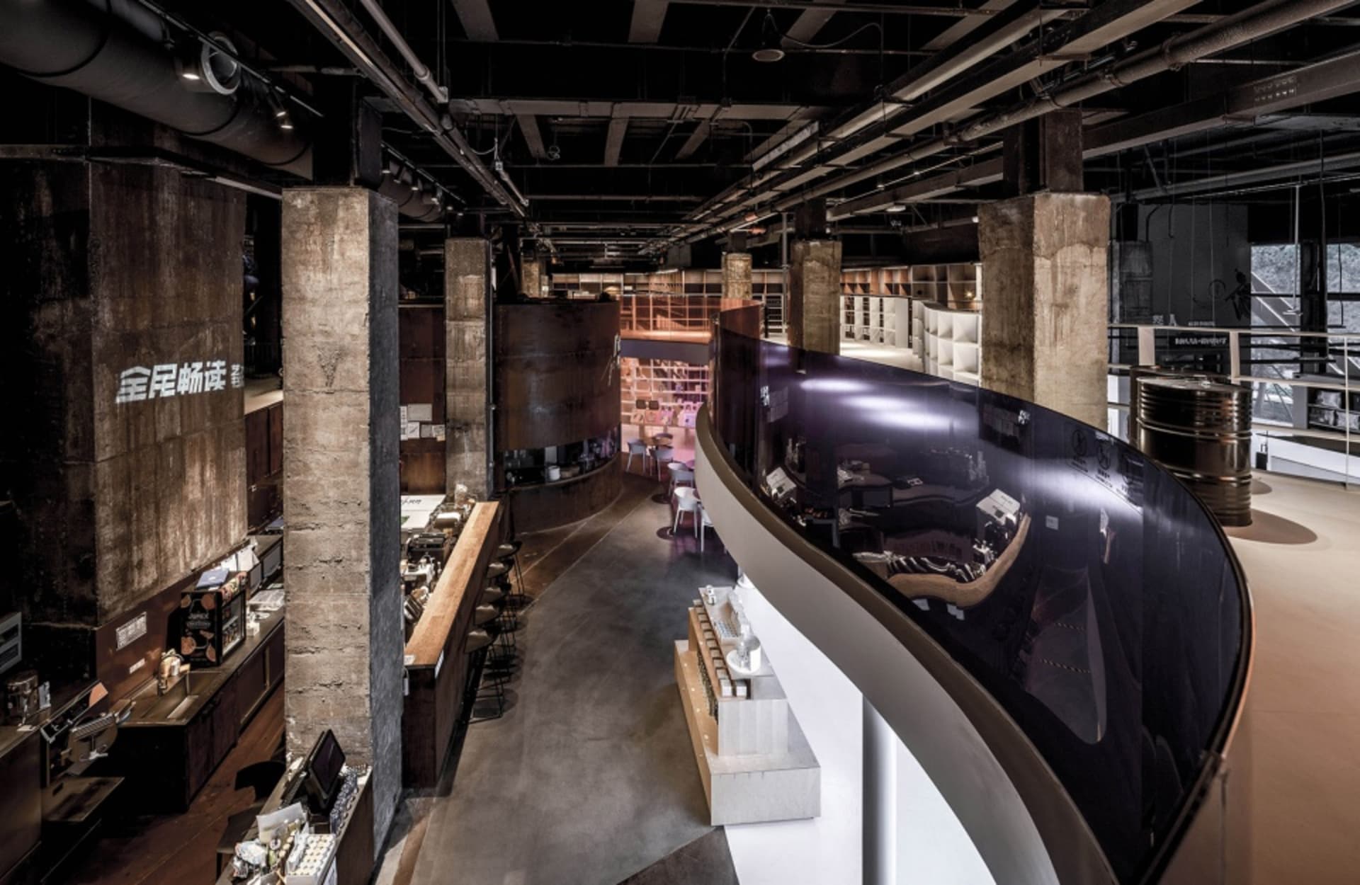 現代工業風咖啡店吧台，裸露混凝土牆面、木質家具與大面窗戶。