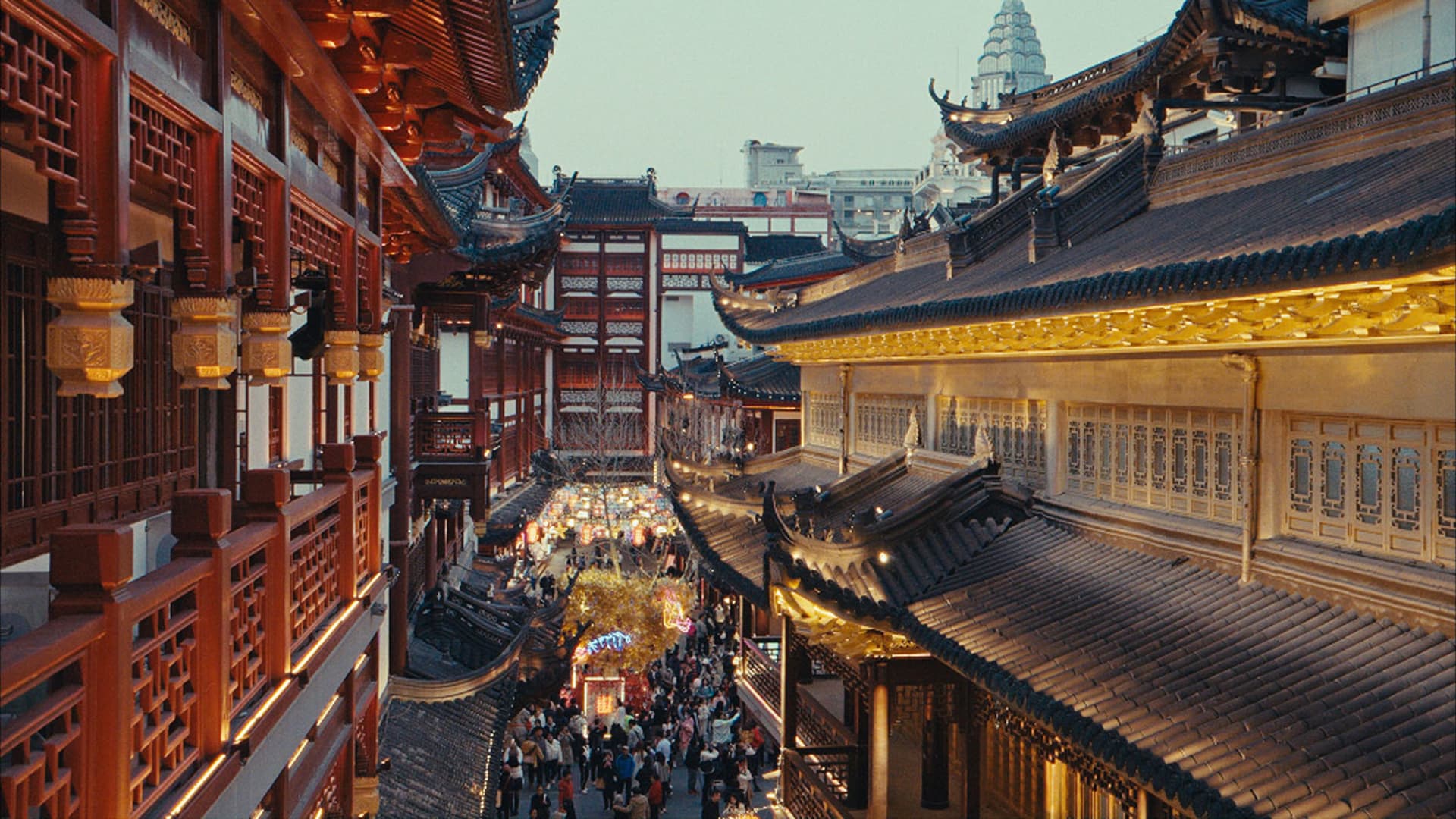 People walking along a traditional Chinese street decorated with illuminated lanterns.