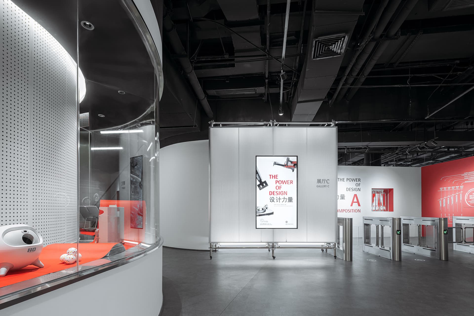 Modern minimalist exhibition space featuring metal and glass elements with a red carpet.