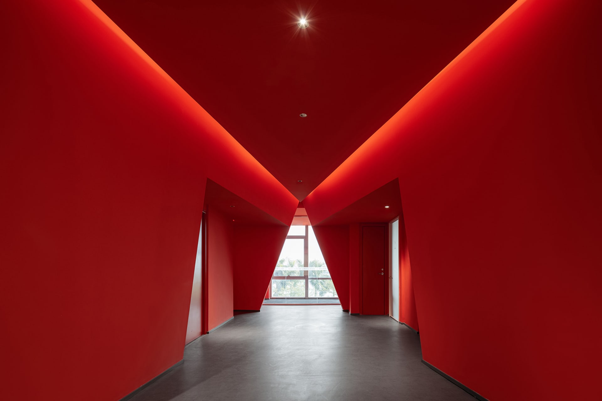 A red corridor with geometric shapes and ceiling lights.