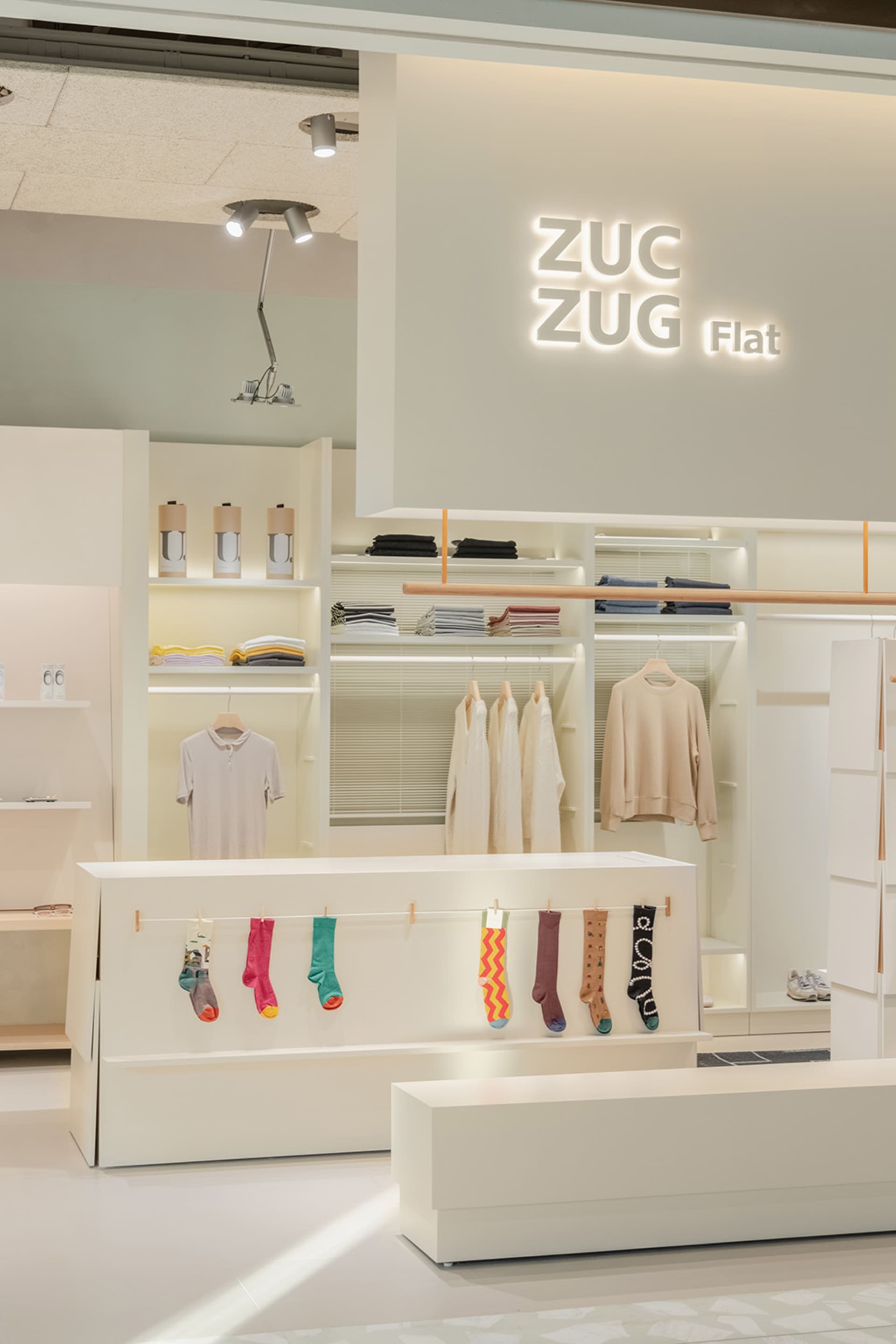 A retail store showcasing clothing on shelves and racks, with a minimalist design.