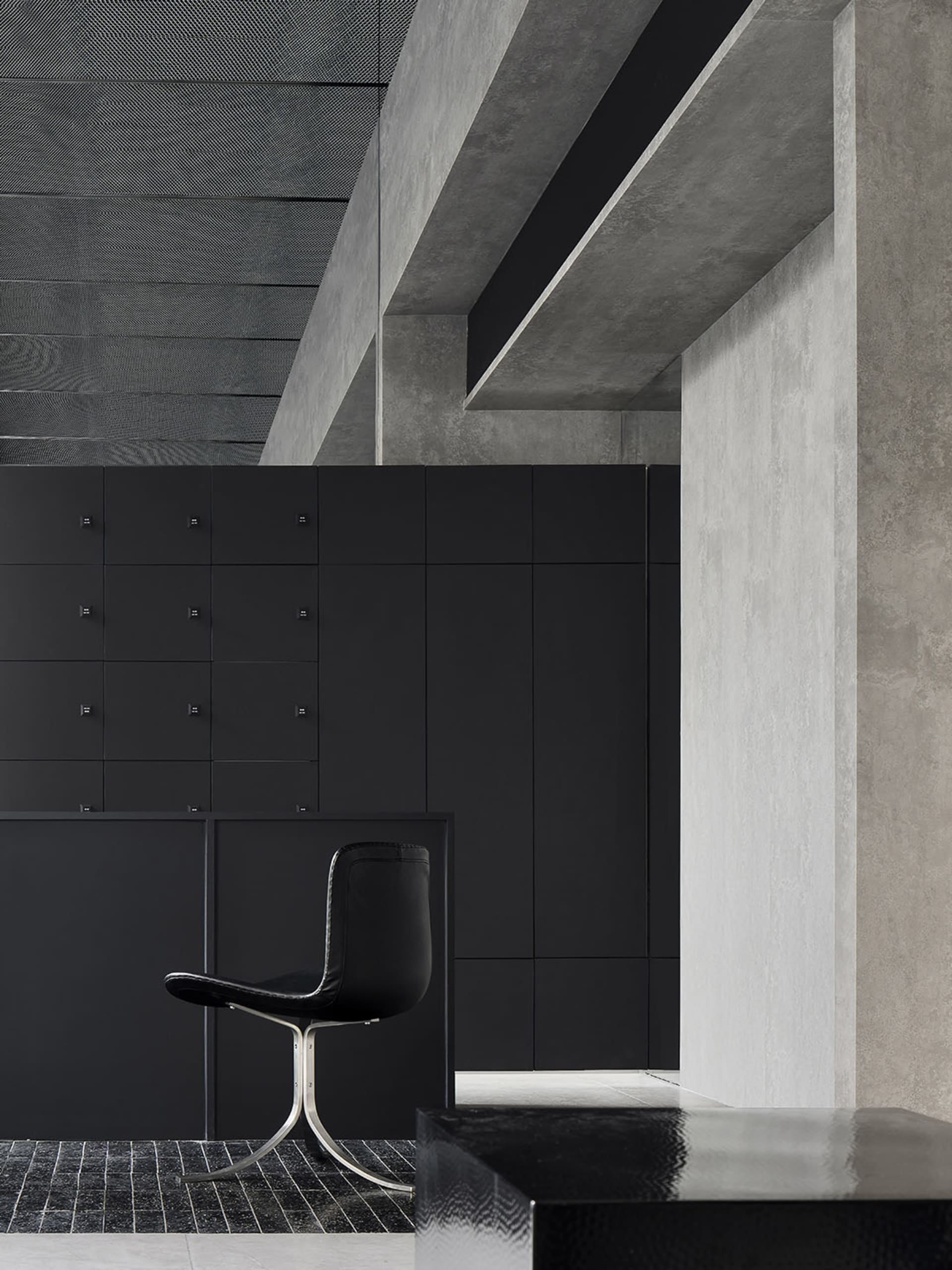 A modern storefront with concrete walls and a sleek, black chair.