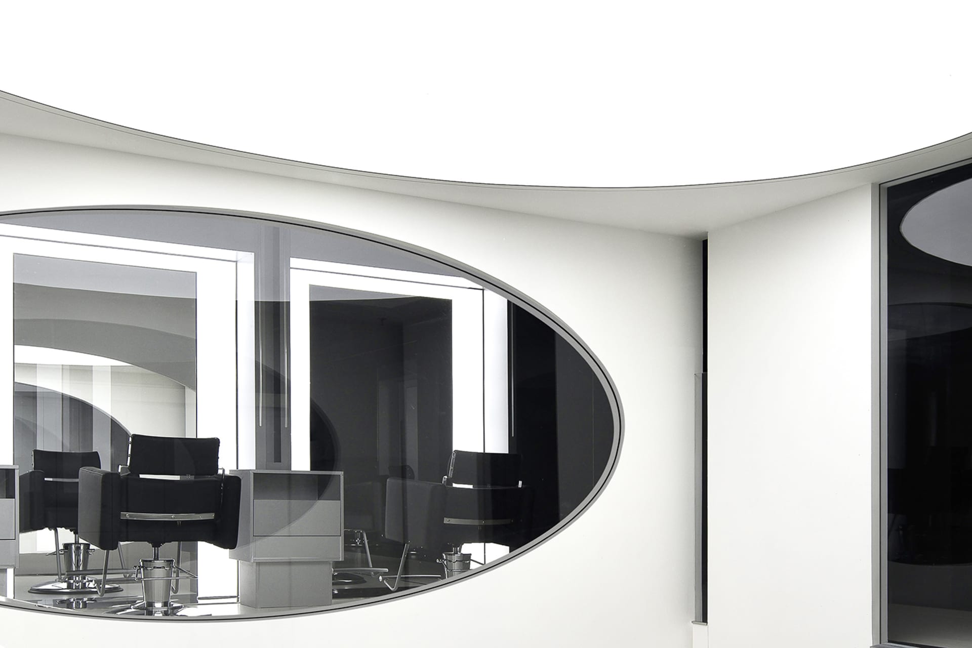 Modern, minimalist salon interior with sleek black chairs and white walls.