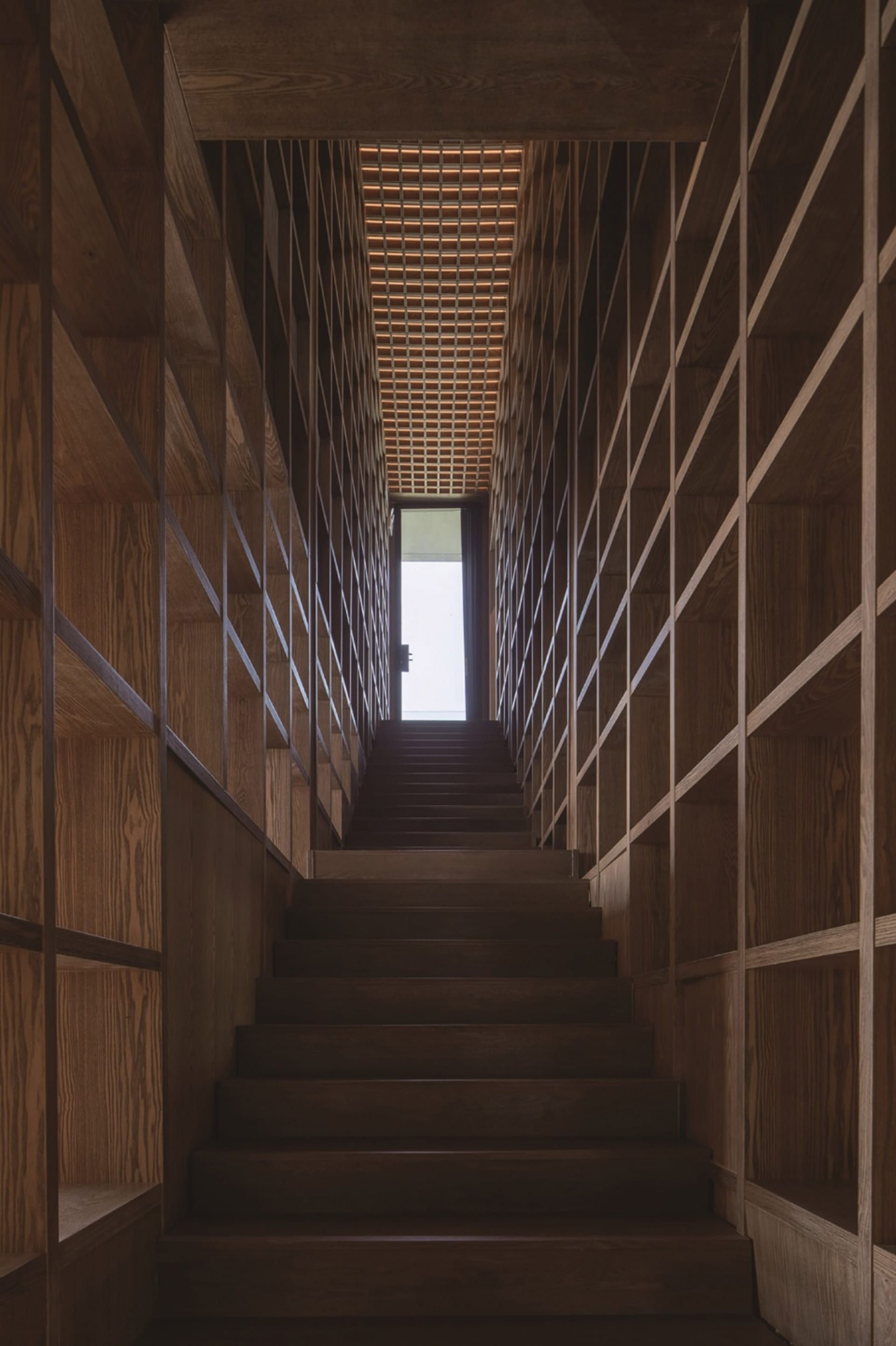 A wooden staircase with an illuminated ceiling and wall panels.