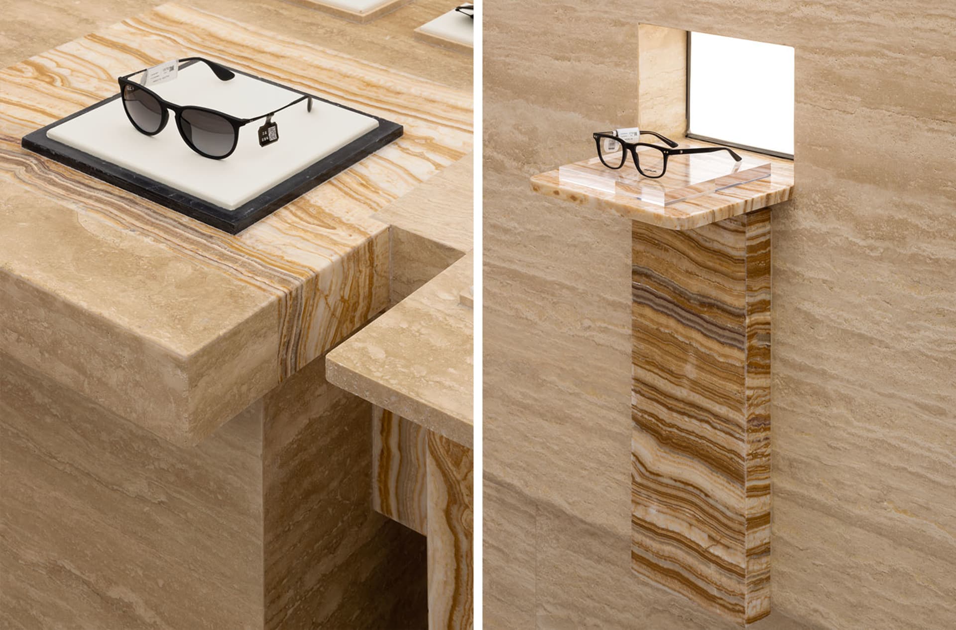 A stylish retail display featuring black sunglasses and a clear spectacle frame placed on a marble surface and pedestal.