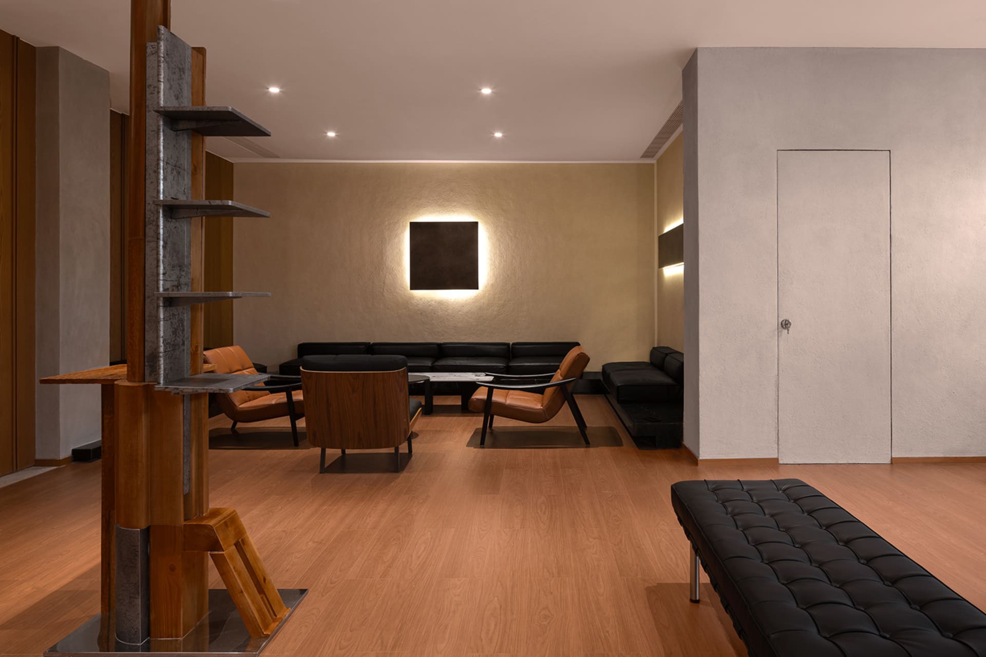 Modern minimalist living room featuring black leather furniture and wooden accents on a brown wooden floor.
