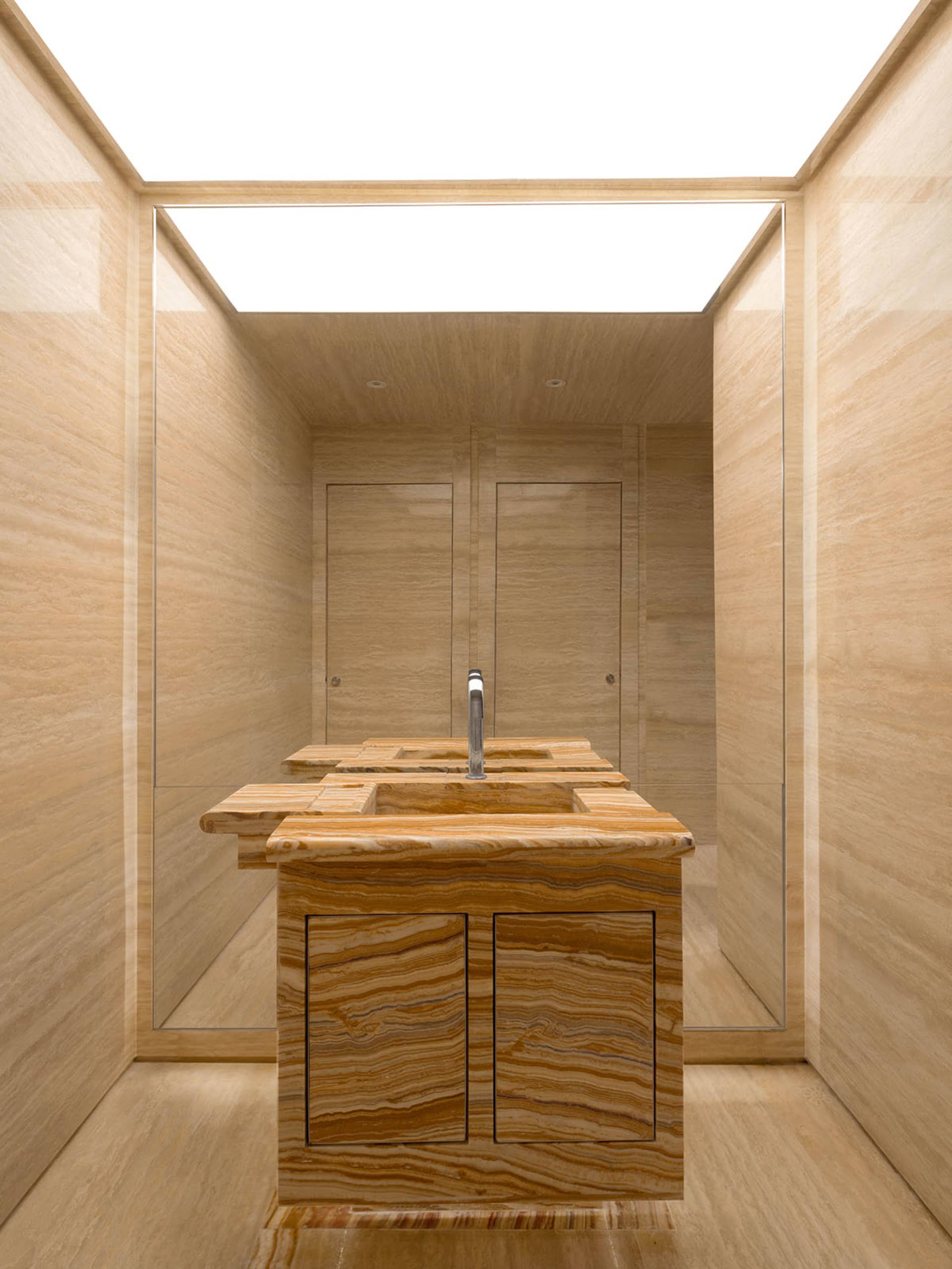 Modern minimalist bathroom with marble fixtures and light wood flooring.