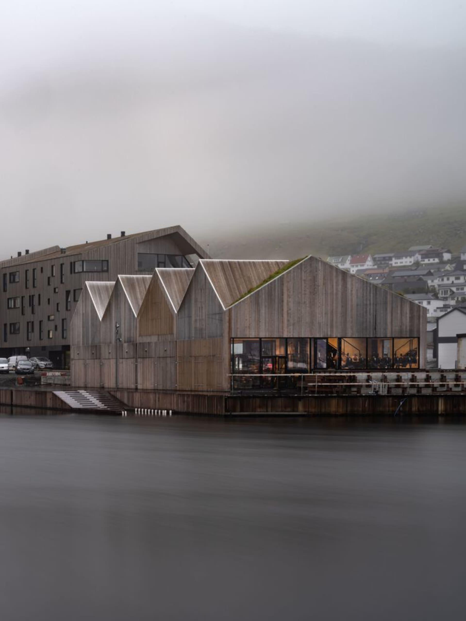A modern industrial wooden building with a sloped roof and large glass windows.