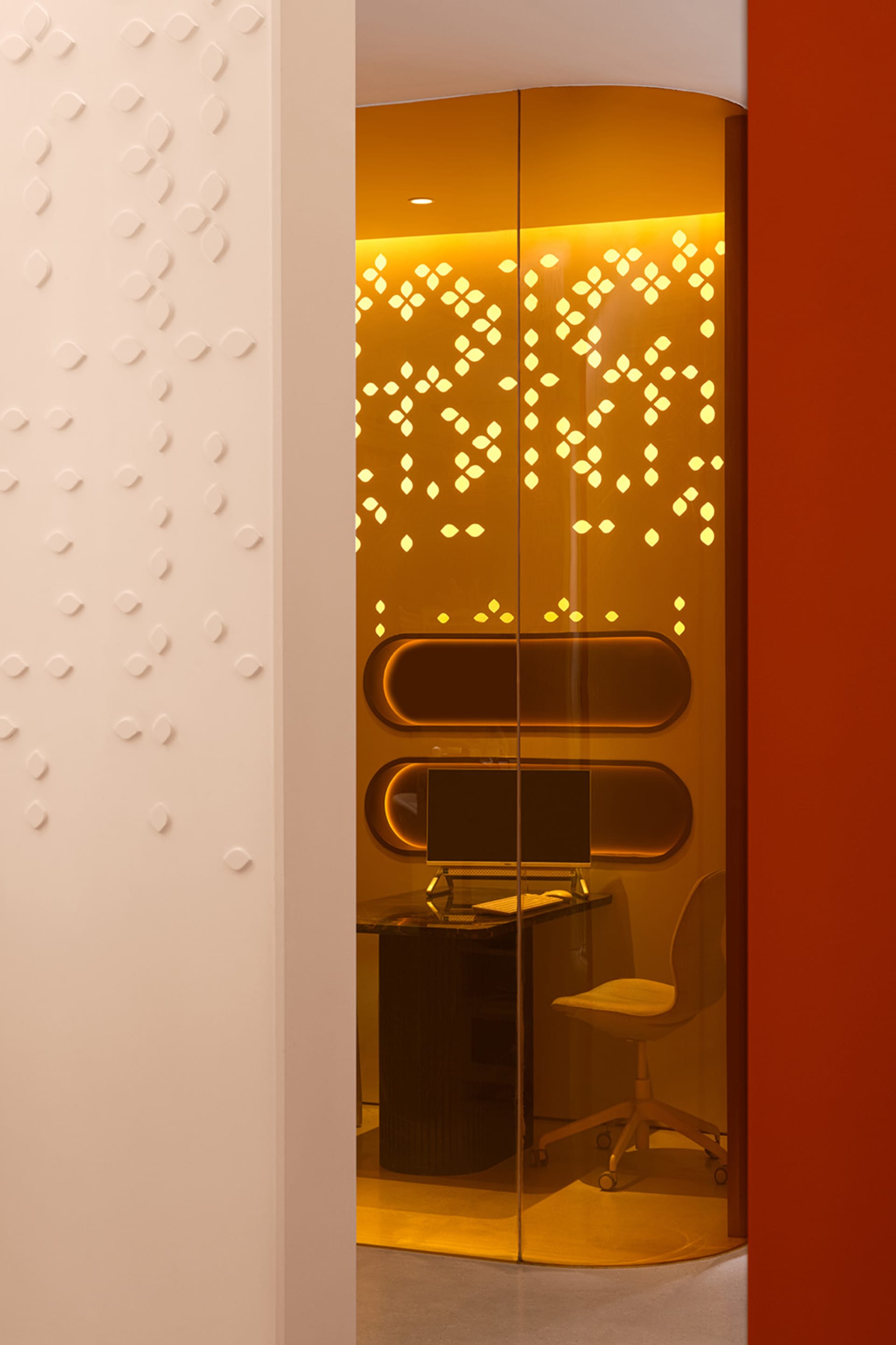 A minimalist office glass booth illuminated with warm lighting, featuring a modern workspace design.