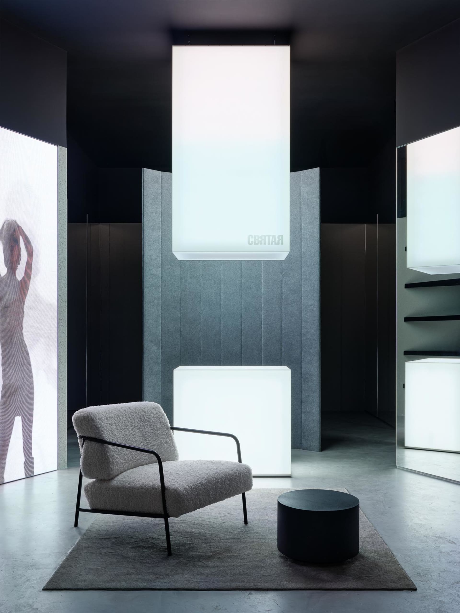A modern living room featuring a fabric upholstered chair, acoustic panels, and acoustic lighting.