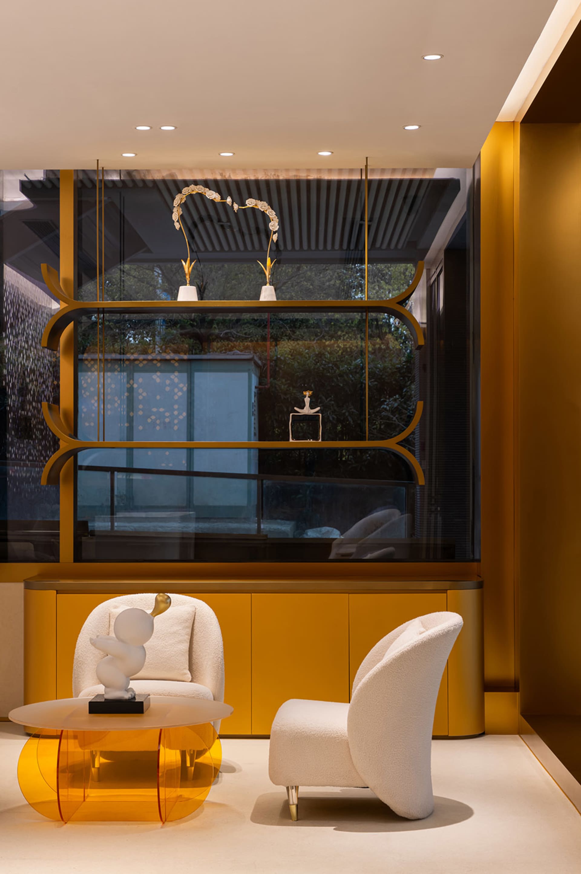 A modern living room features glass walls, wood accents, and fabric furniture.
