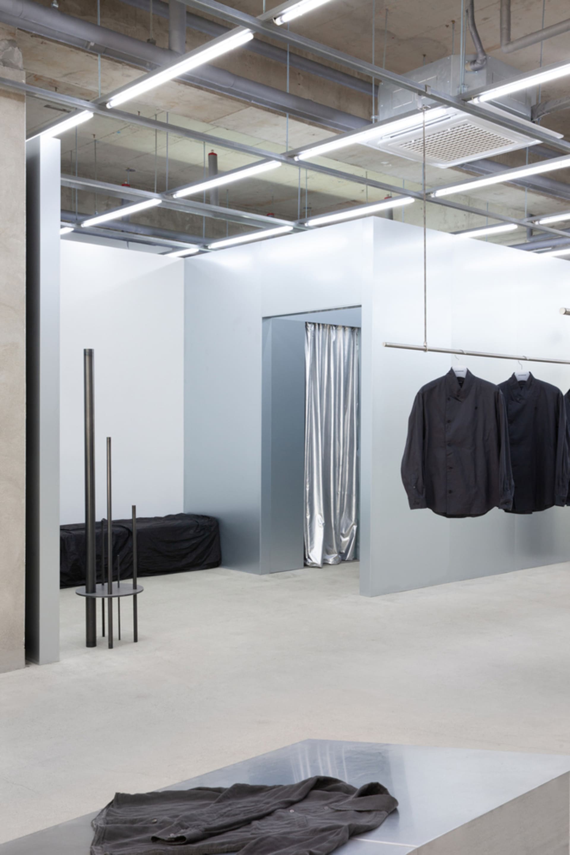 Modern retail store with minimalist design, featuring concrete walls and a metal counter.