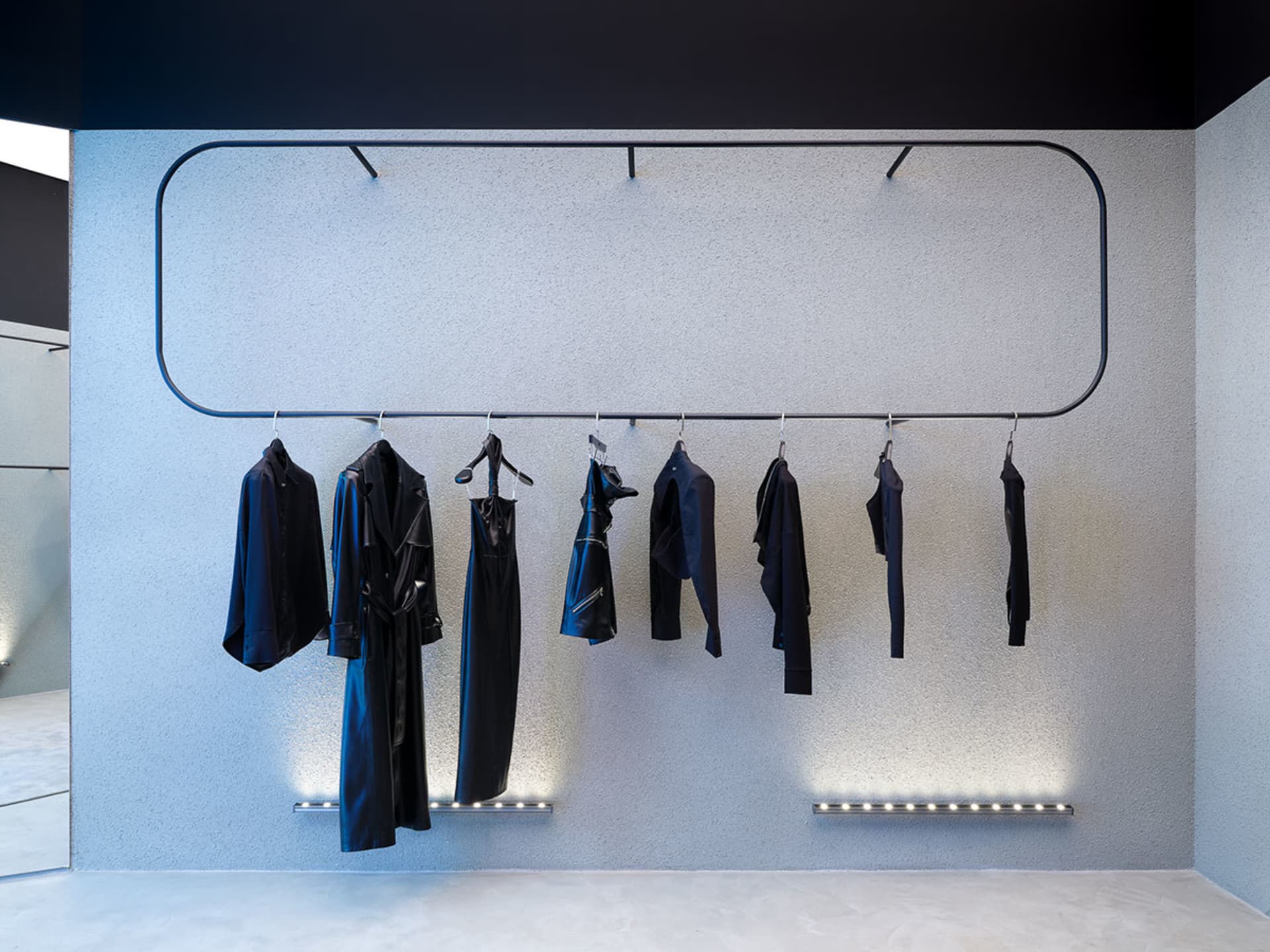 A sophisticated clothing display featuring black garments on metal racks in a retail interior setting.