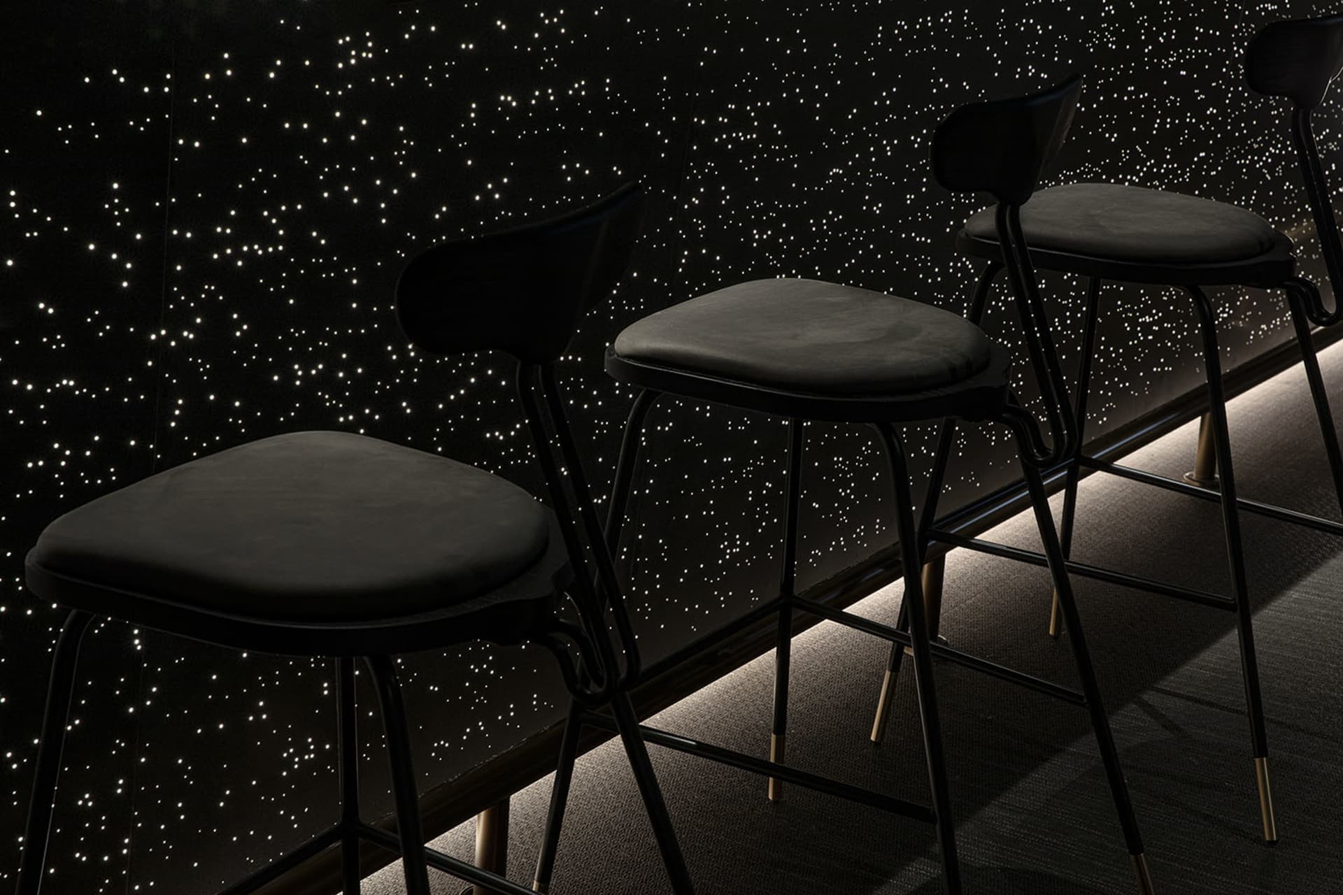 Black minimalist furniture arranged against a starry night sky background.