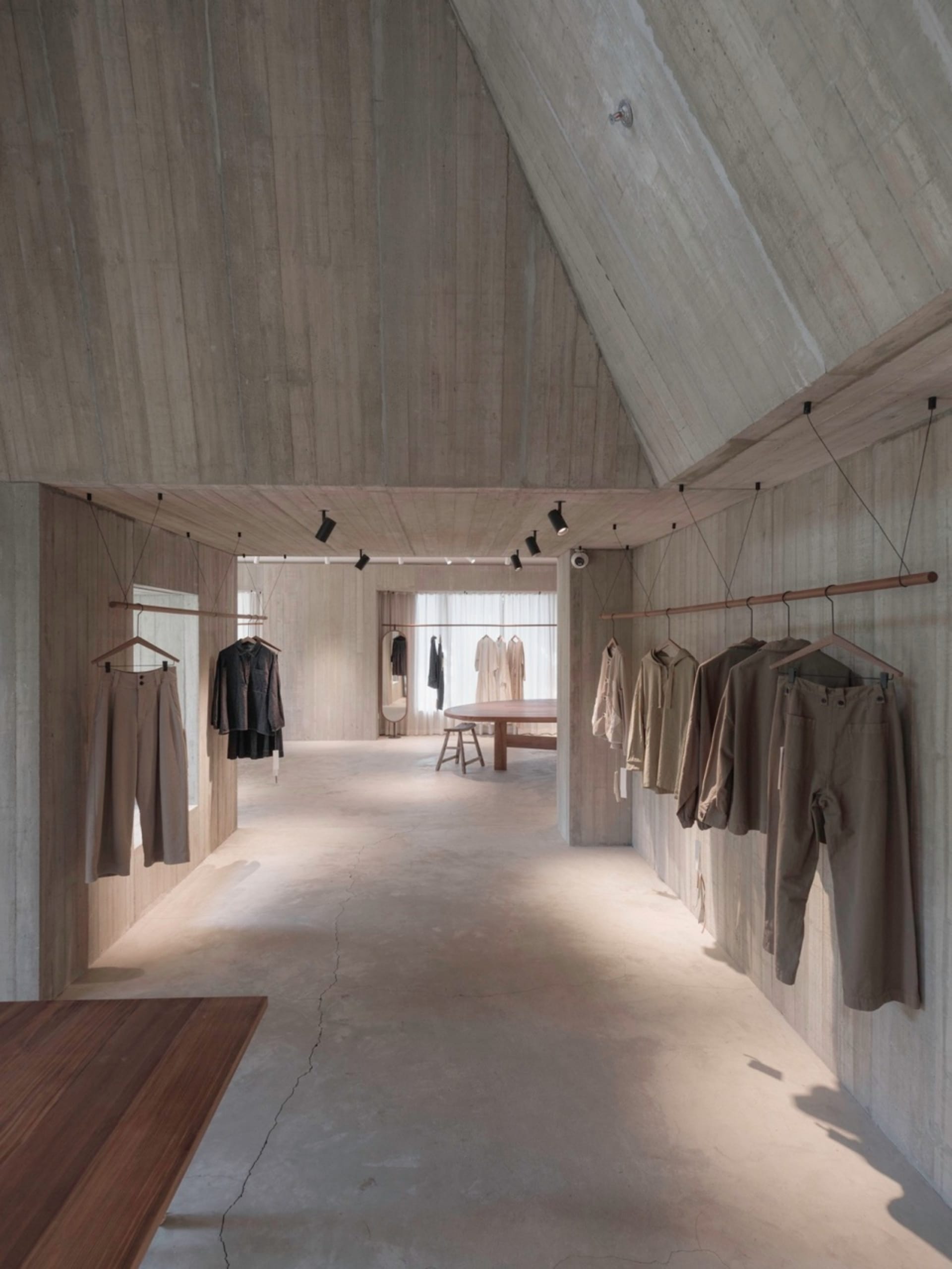 Minimalist clothing retail store with concrete walls and clothing racks.