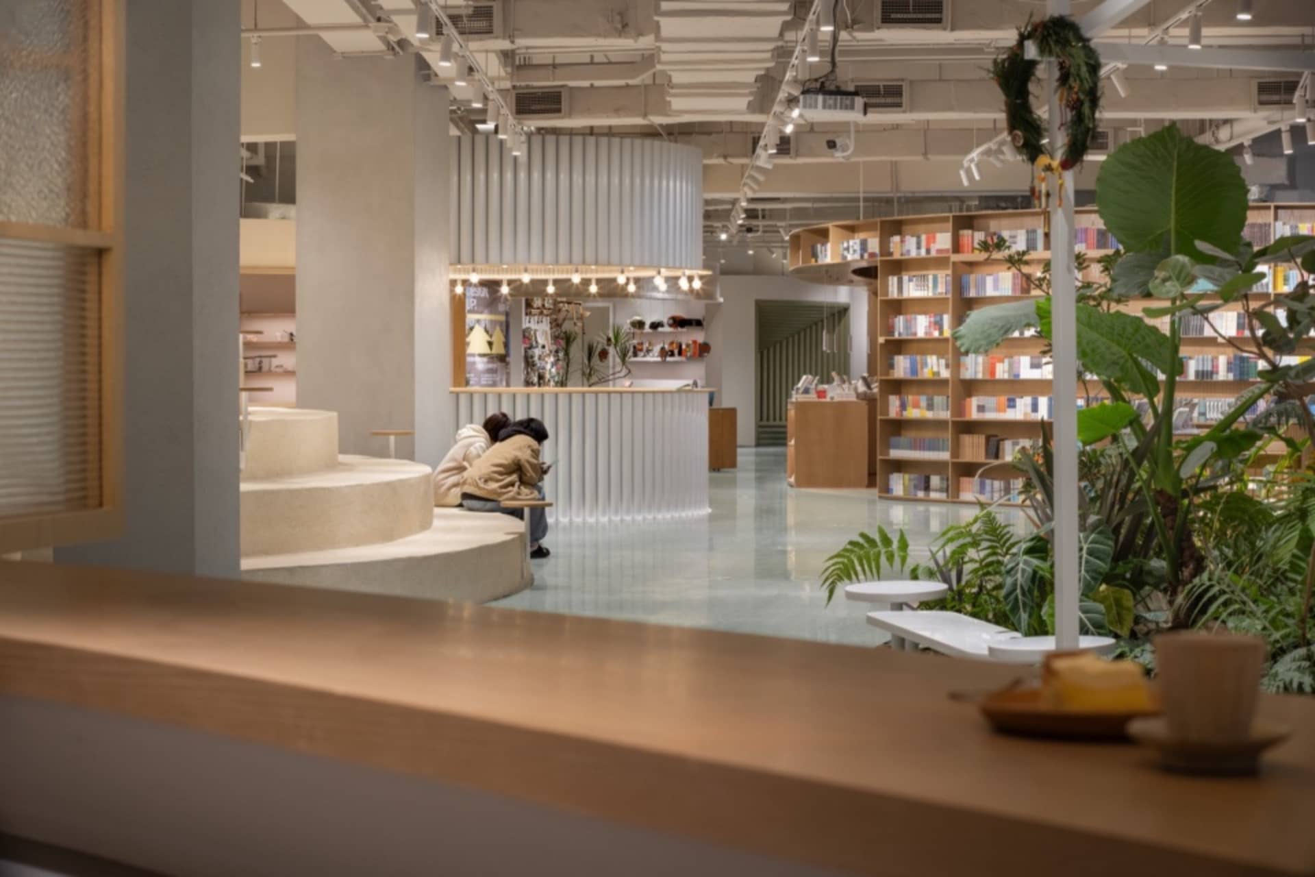 現代圖書館室內,木製書架、混凝土階梯與玻璃元素。