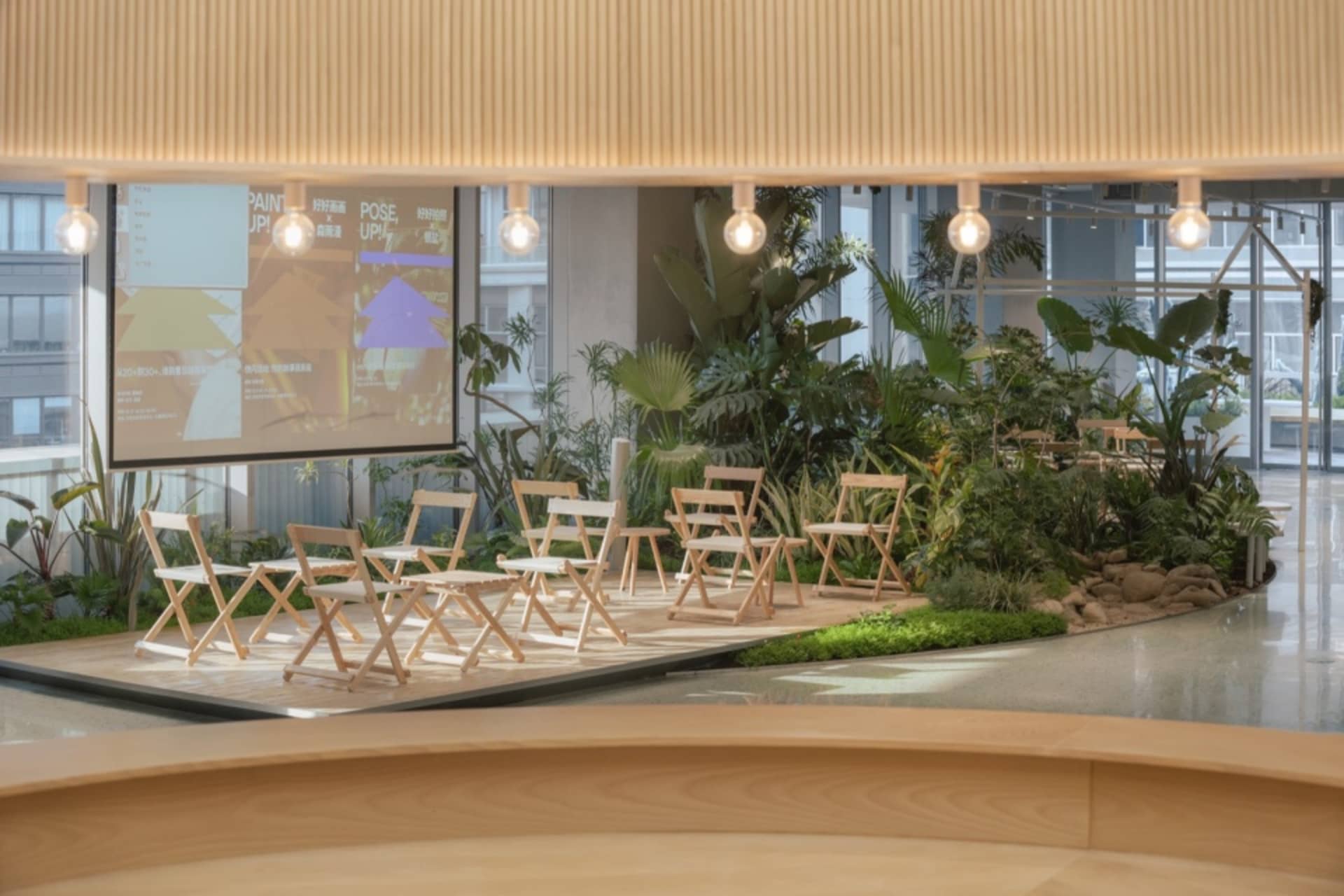 An industrial-style coffee shop with wooden furniture and greenery on a stage-like platform.