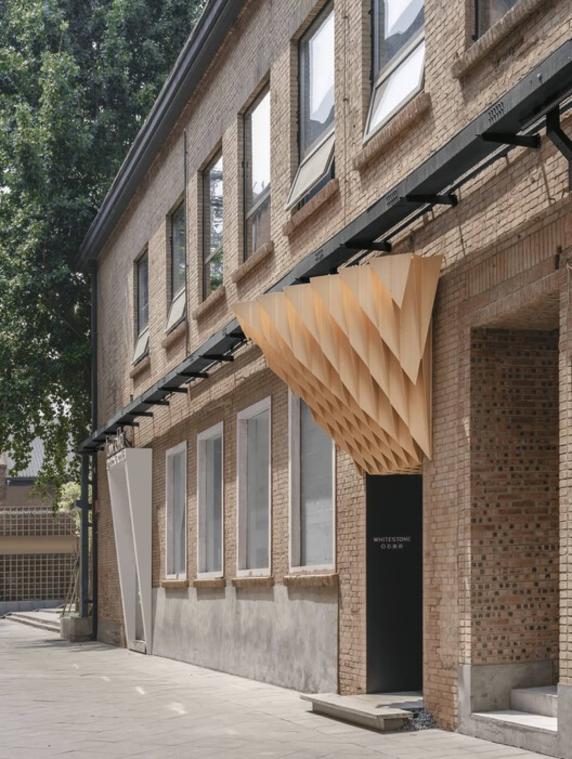 A modern building exterior featuring brick, concrete, and wood materials.