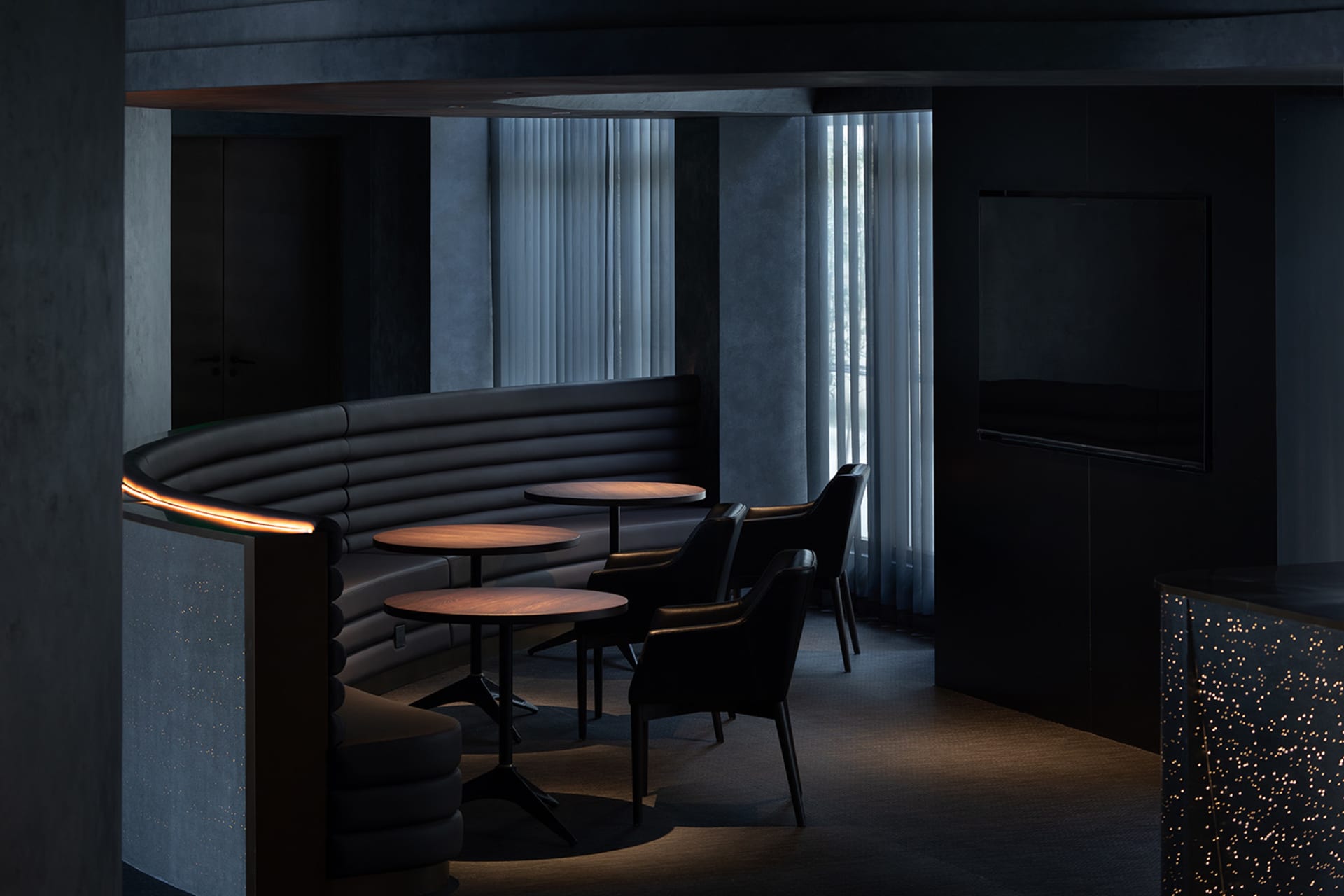 Modern design seating area with round tables and black leather chairs in a restaurant/cafe setting.