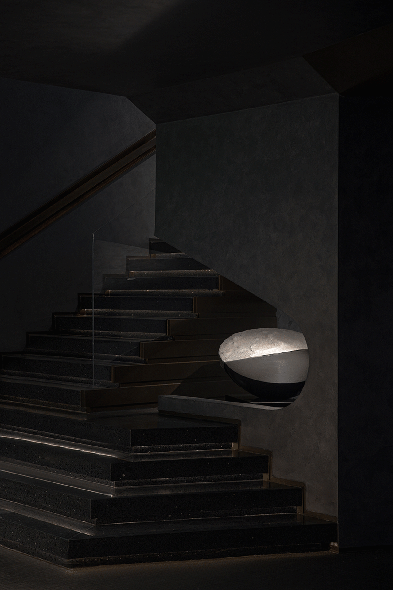 Modern staircase with minimalist design, featuring concrete steps and a glass railing.