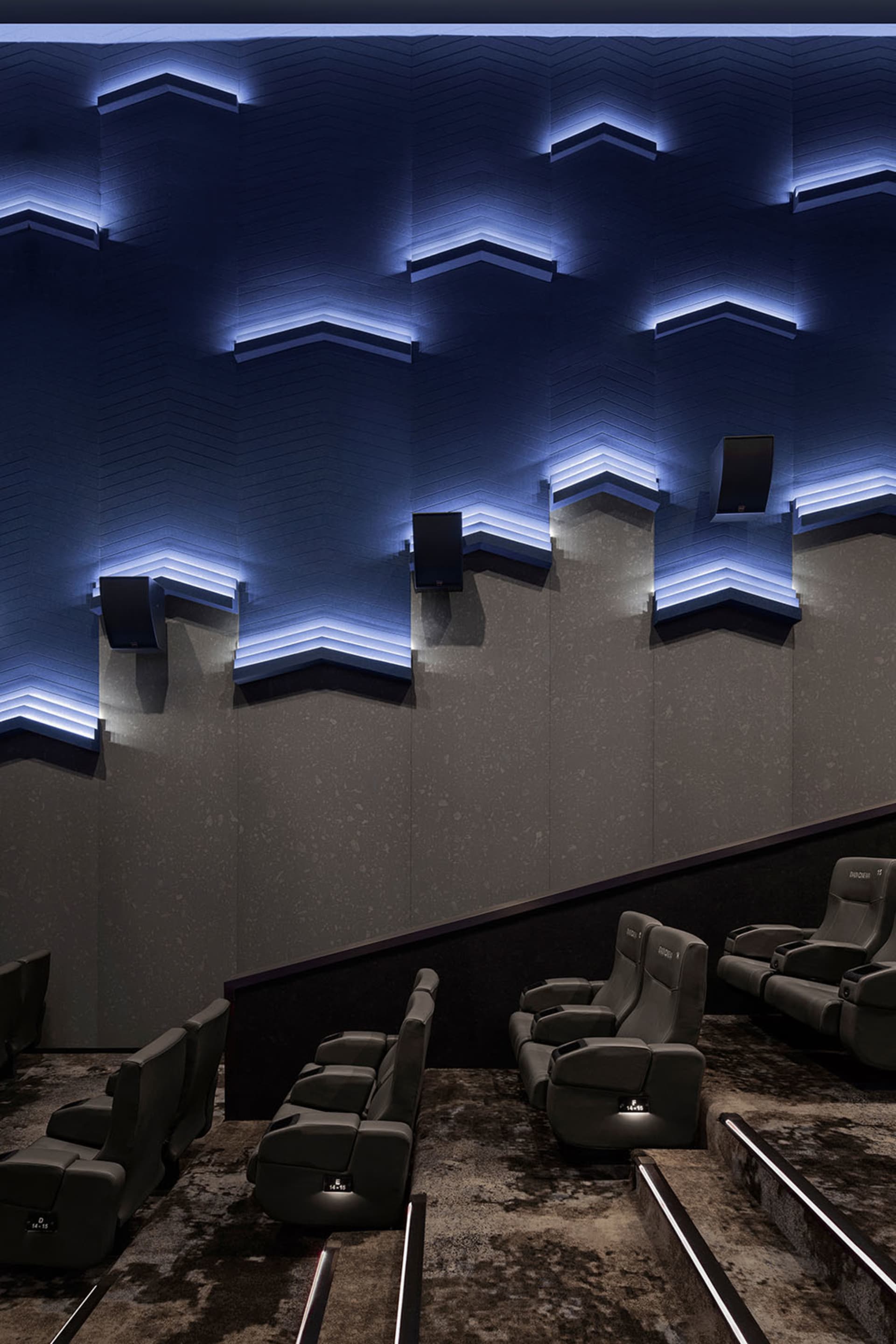 Industrial-style cinema interior with textured concrete walls and modern, ergonomic seating.