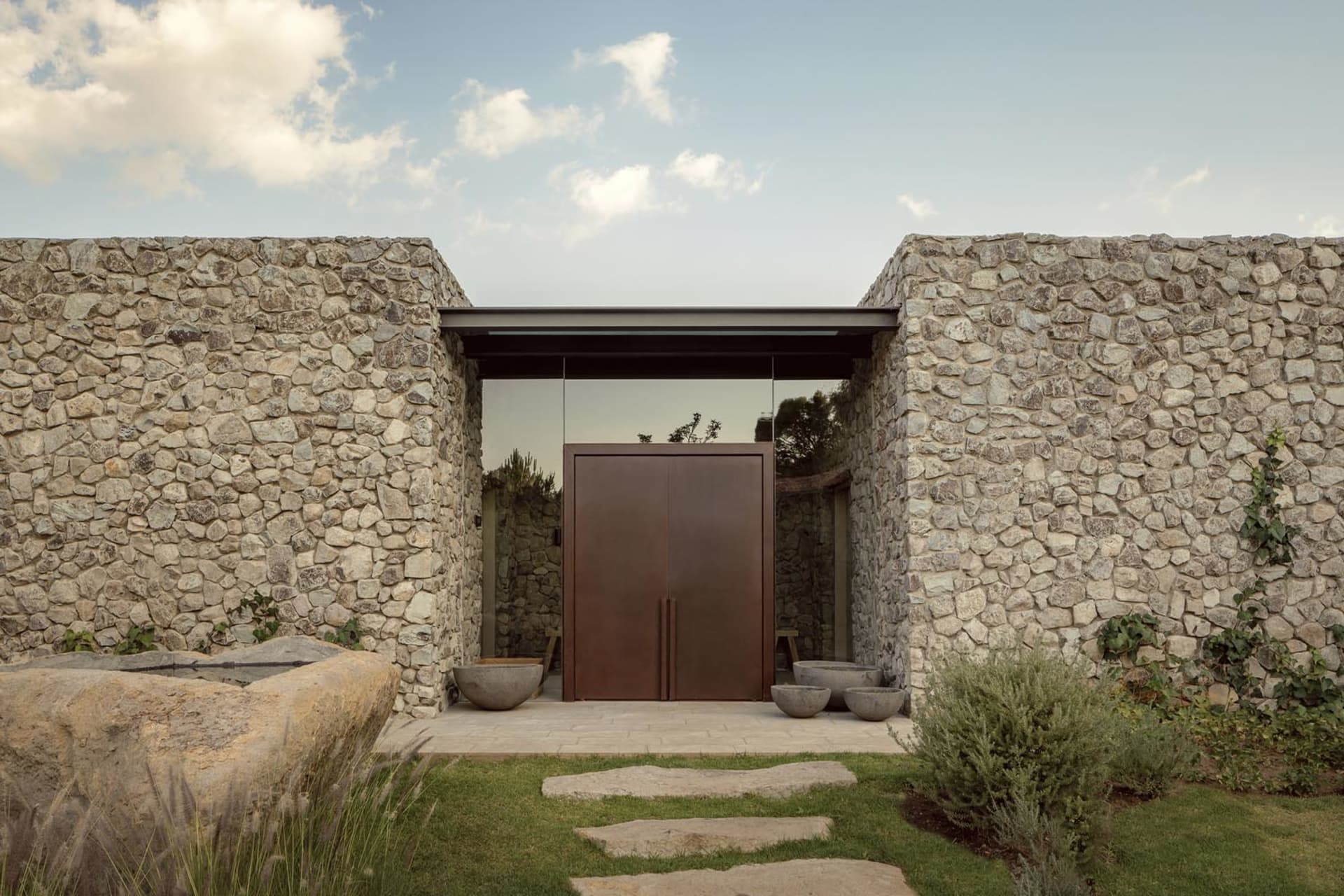 A modern house exterior made of stone with a large glass door.