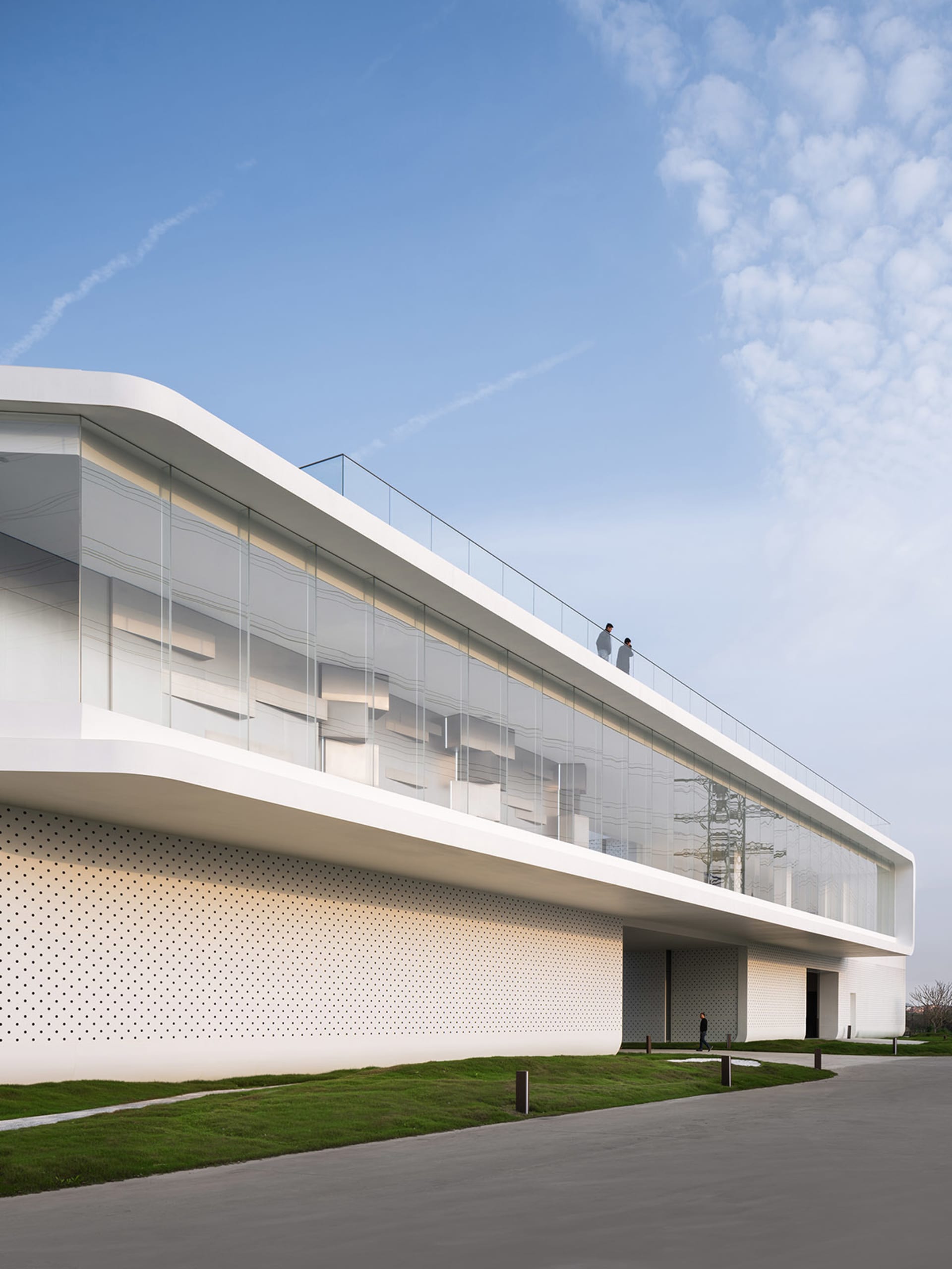 Modern architectural building with transparent glass facade and white perforated wall