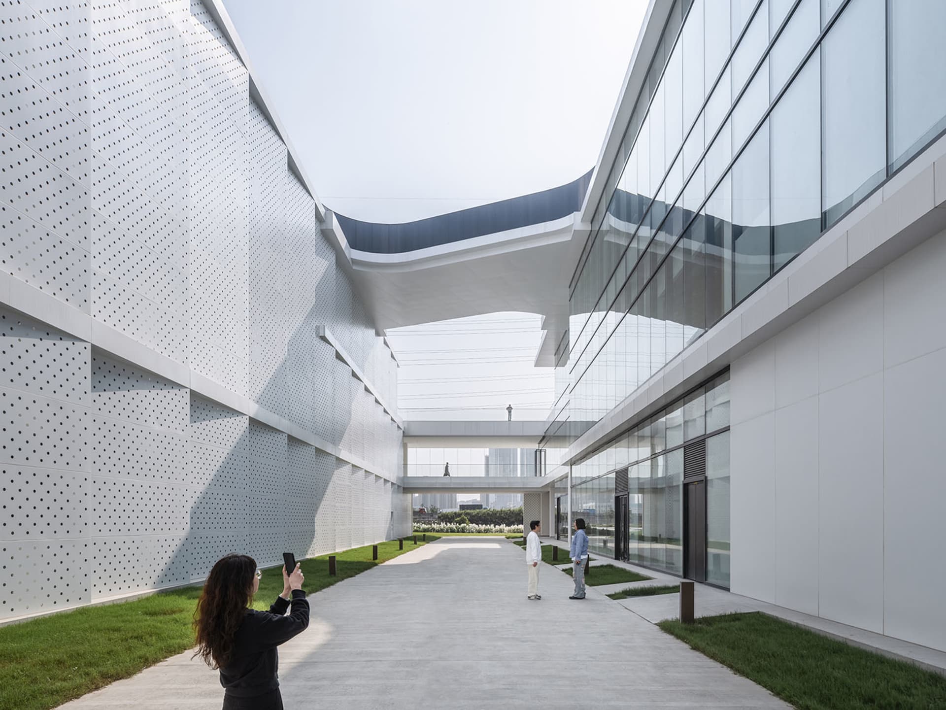 People walking in a modern exterior space with glass and concrete materials.