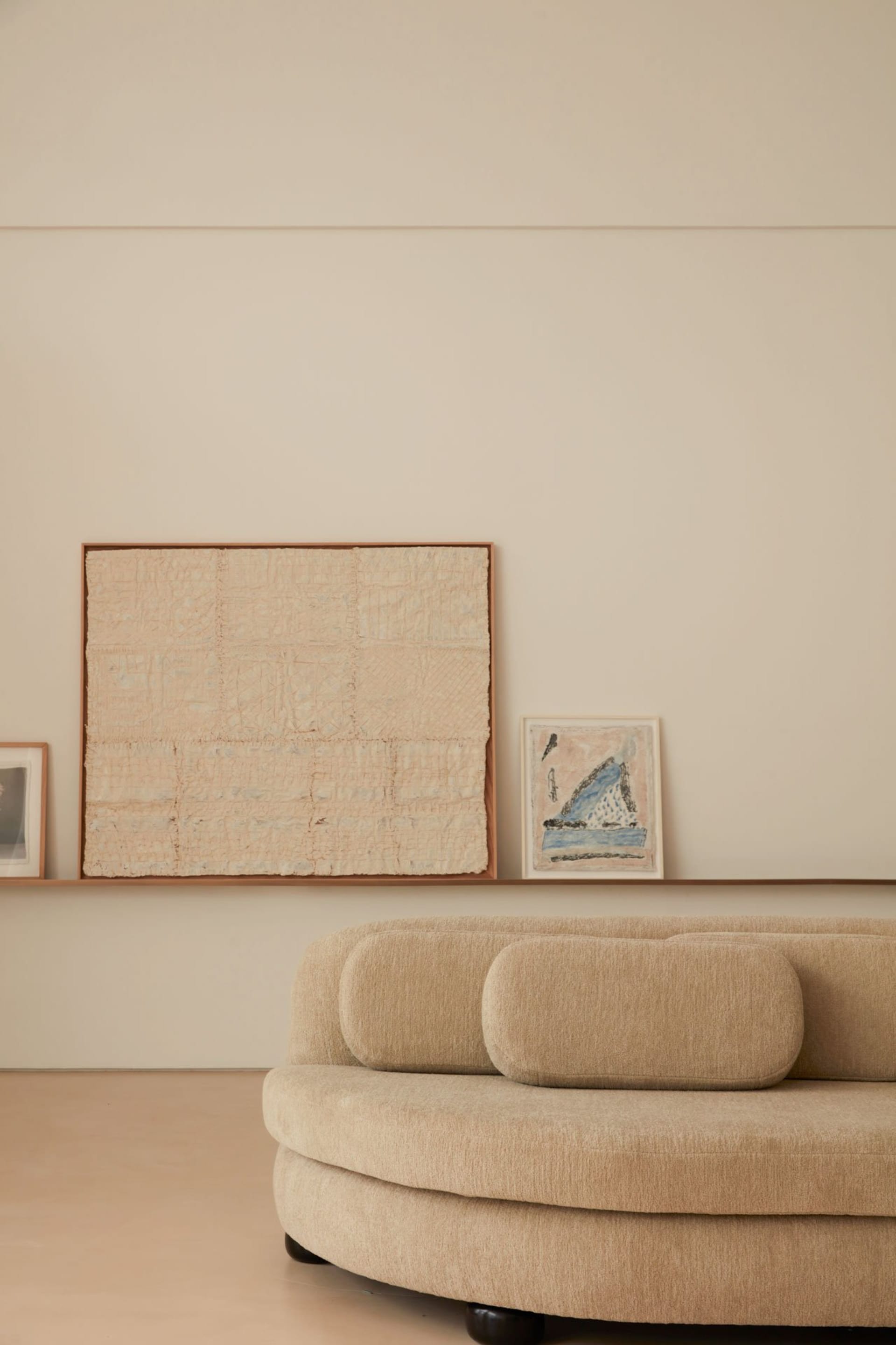 Modern circular sofa with neutral fabric upholstery against a minimalist backdrop with abstract artwork.