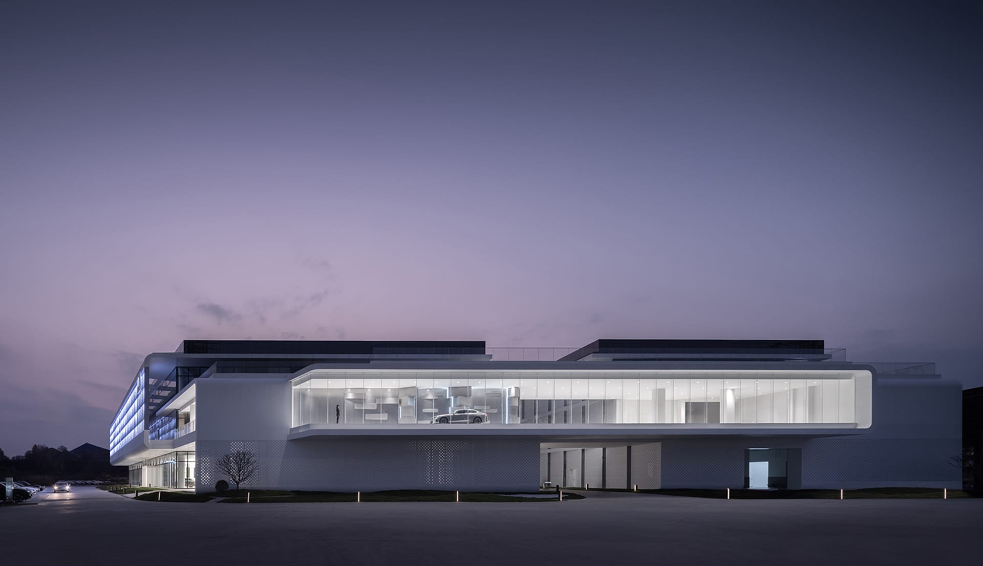 A modern commercial building with extensive glass façade at dusk.