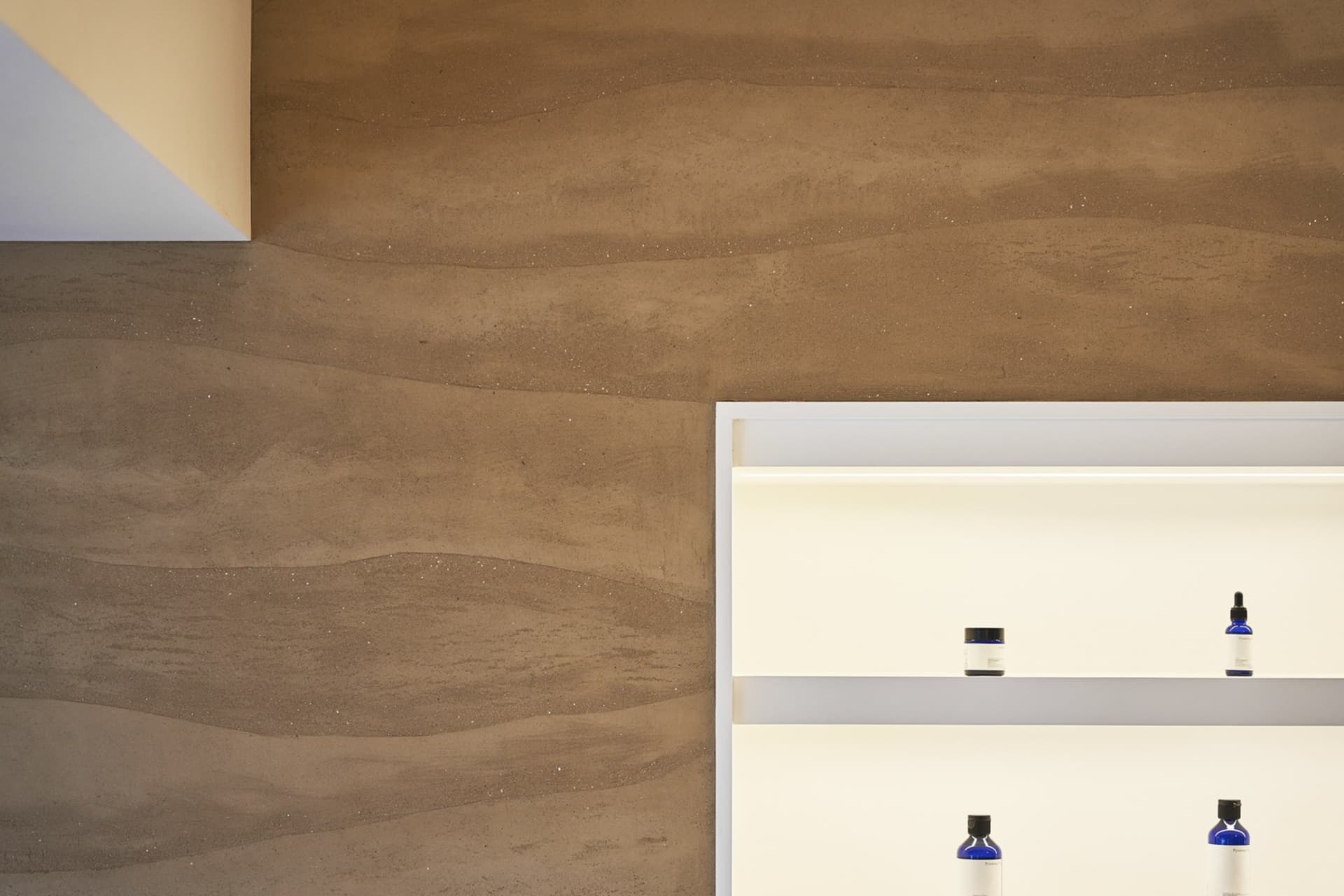 A minimalist storefront with a textured concrete wall.
