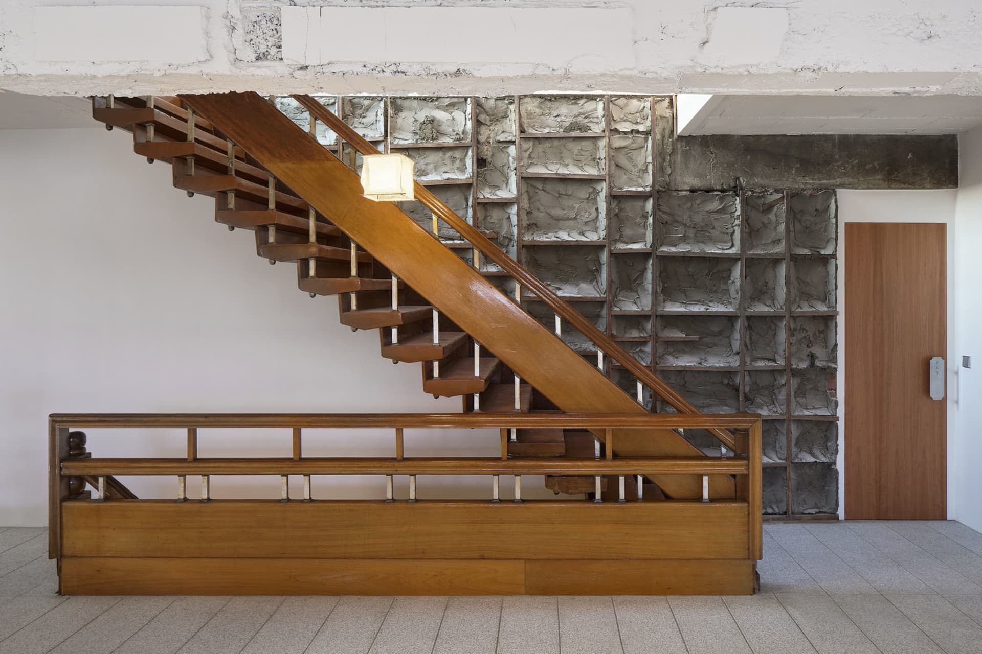 A modern wooden staircase with a concrete wall and surrounding structure.