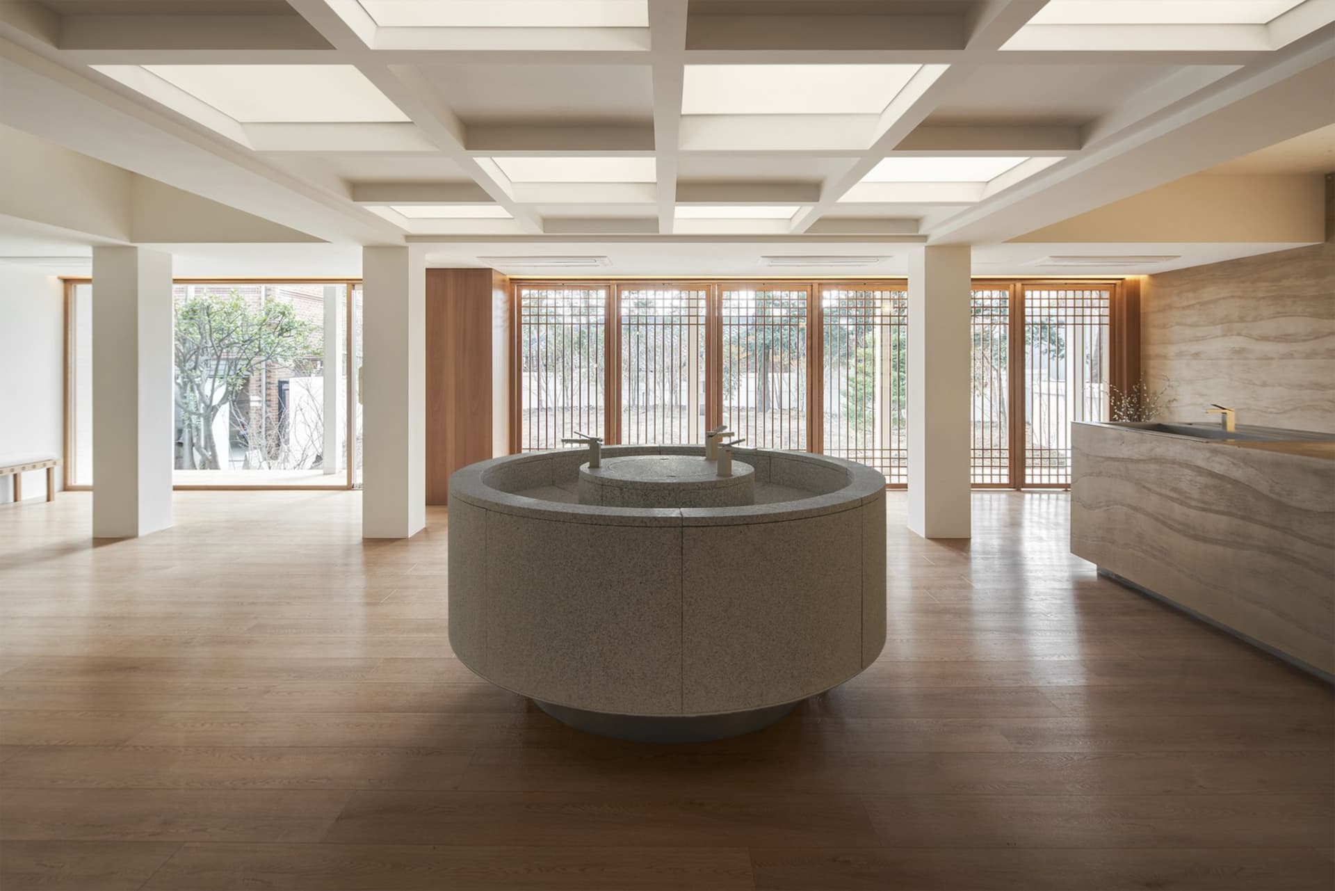 Modern hotel lobby with natural stone flooring and a circular central feature.