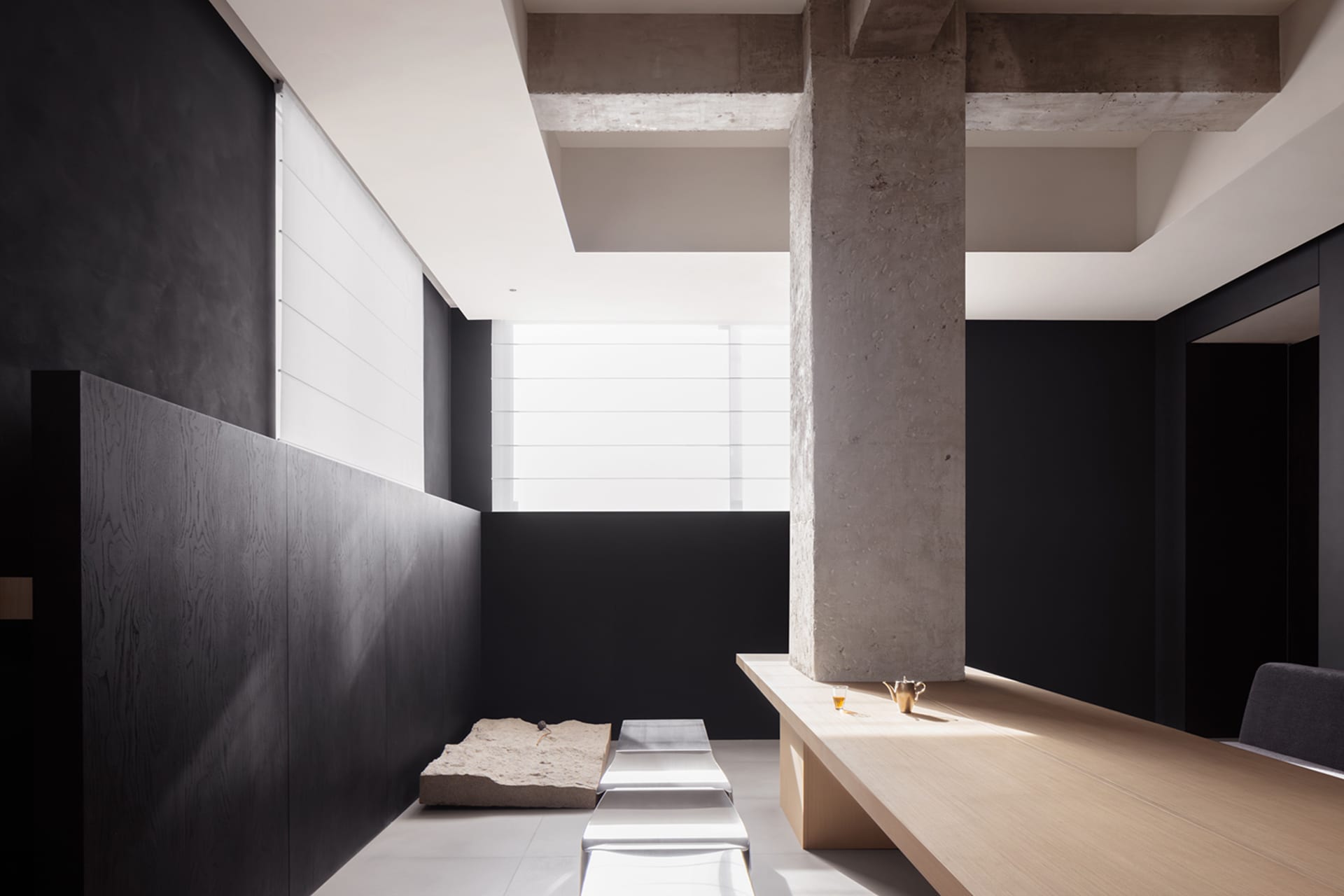 A contemporary living room designed with minimalist aesthetics, featuring concrete and wooden elements.