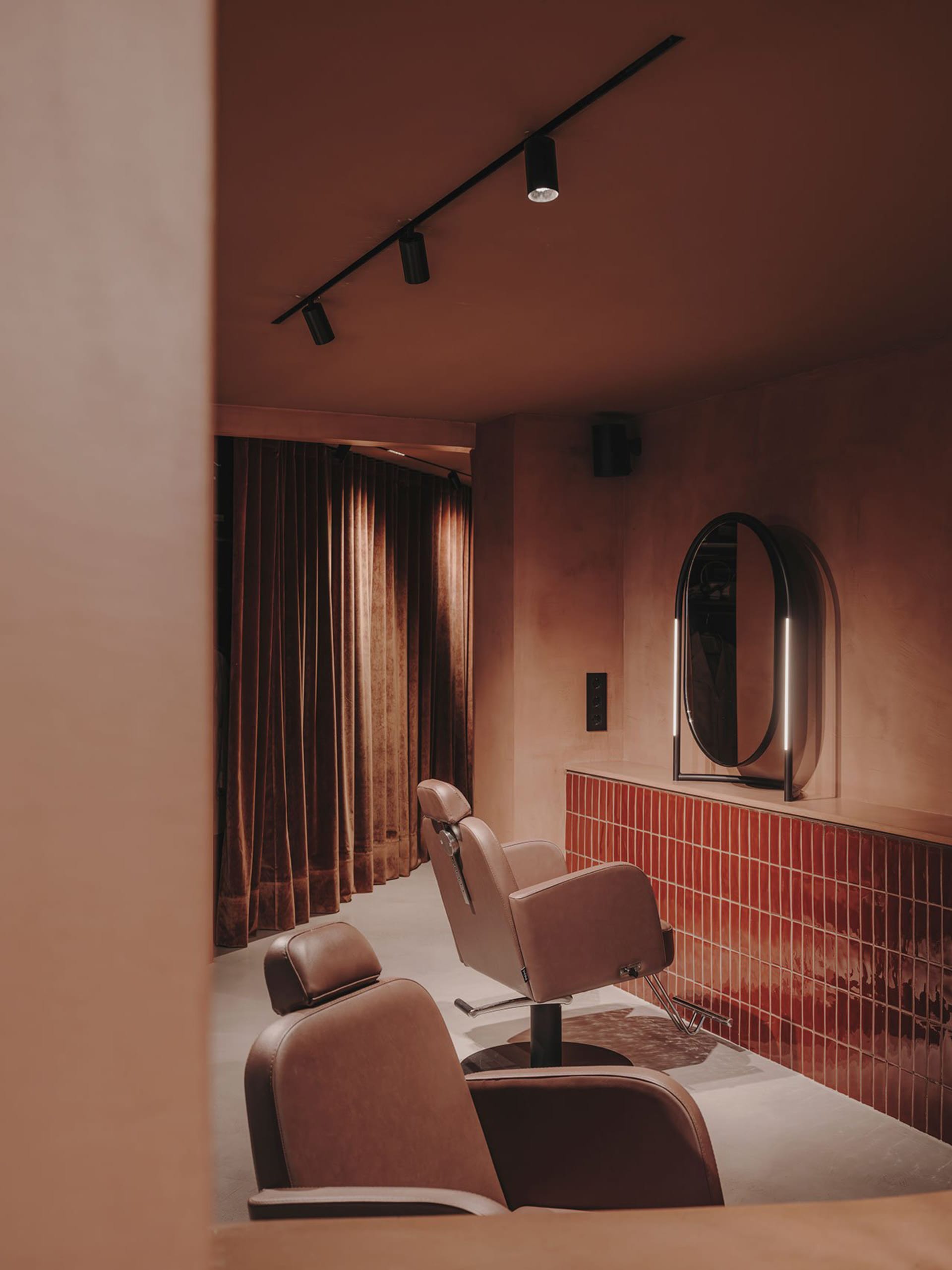 Modern minimalist salon with brown leather chairs, tiled flooring, and a sleek design aesthetic.