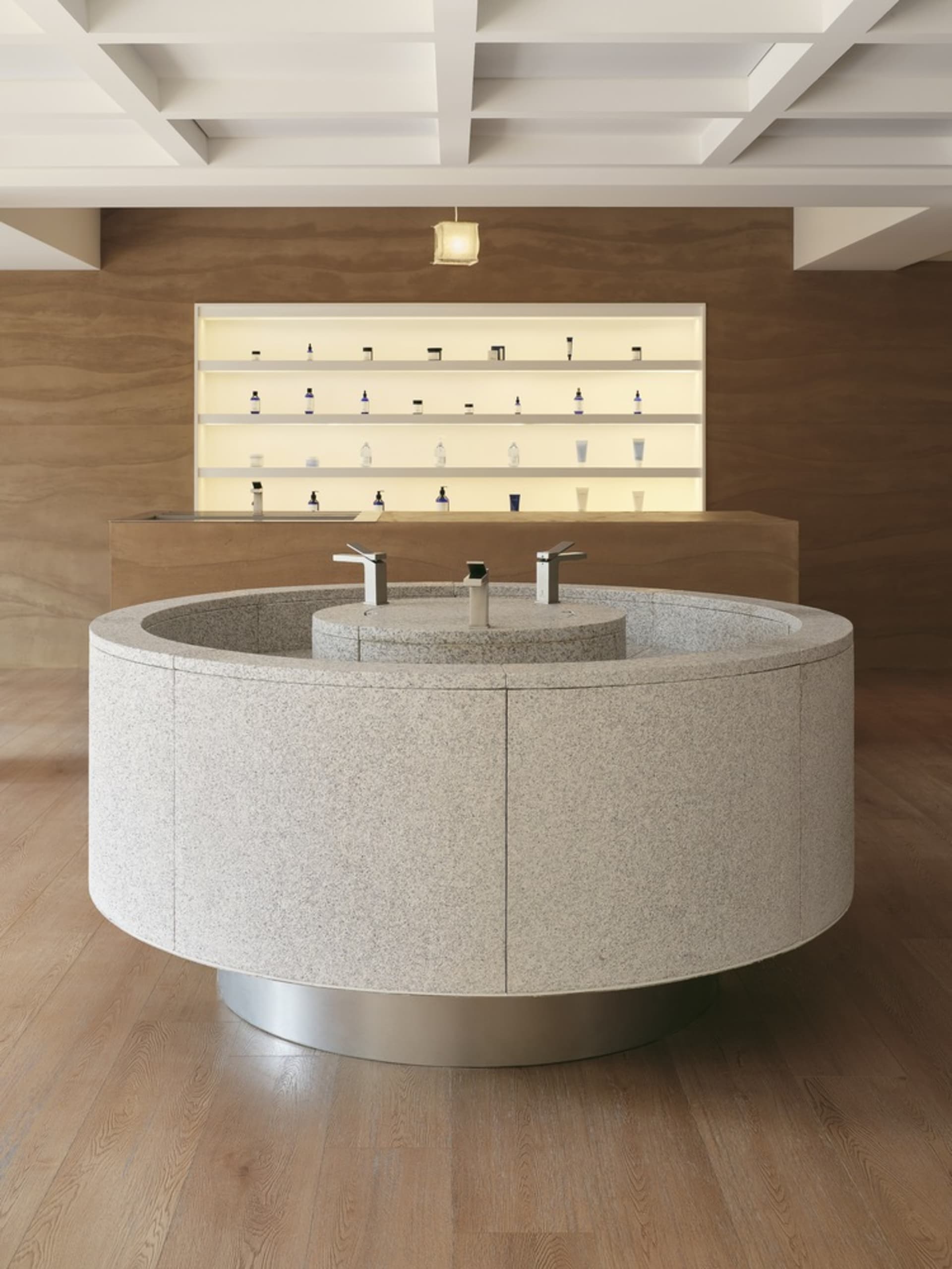 Modern retail storefront featuring a circular granite countertop with two faucets in a minimalist space.