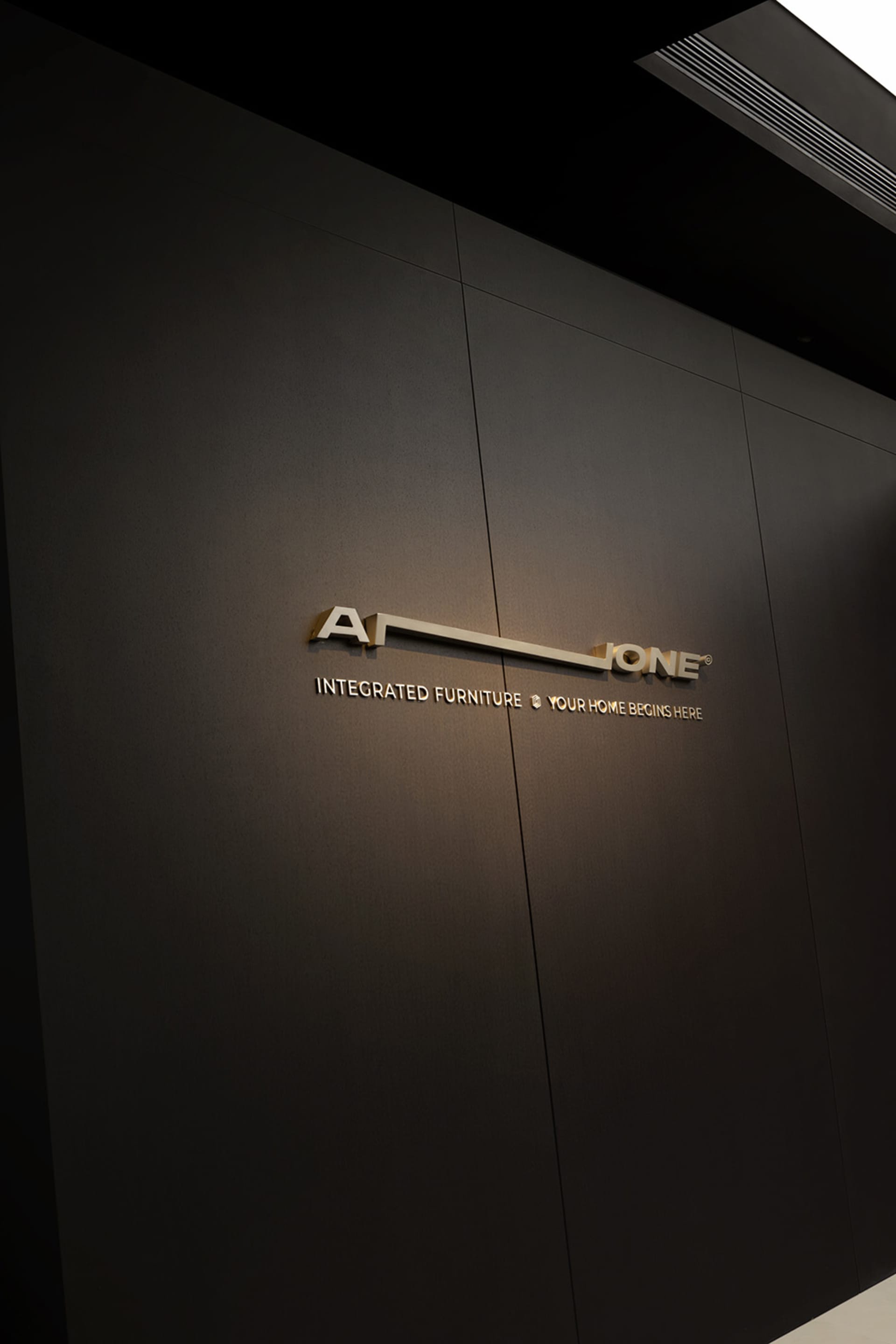 Interior shot of a minimalist corporate office entrance with a metal logo sign.