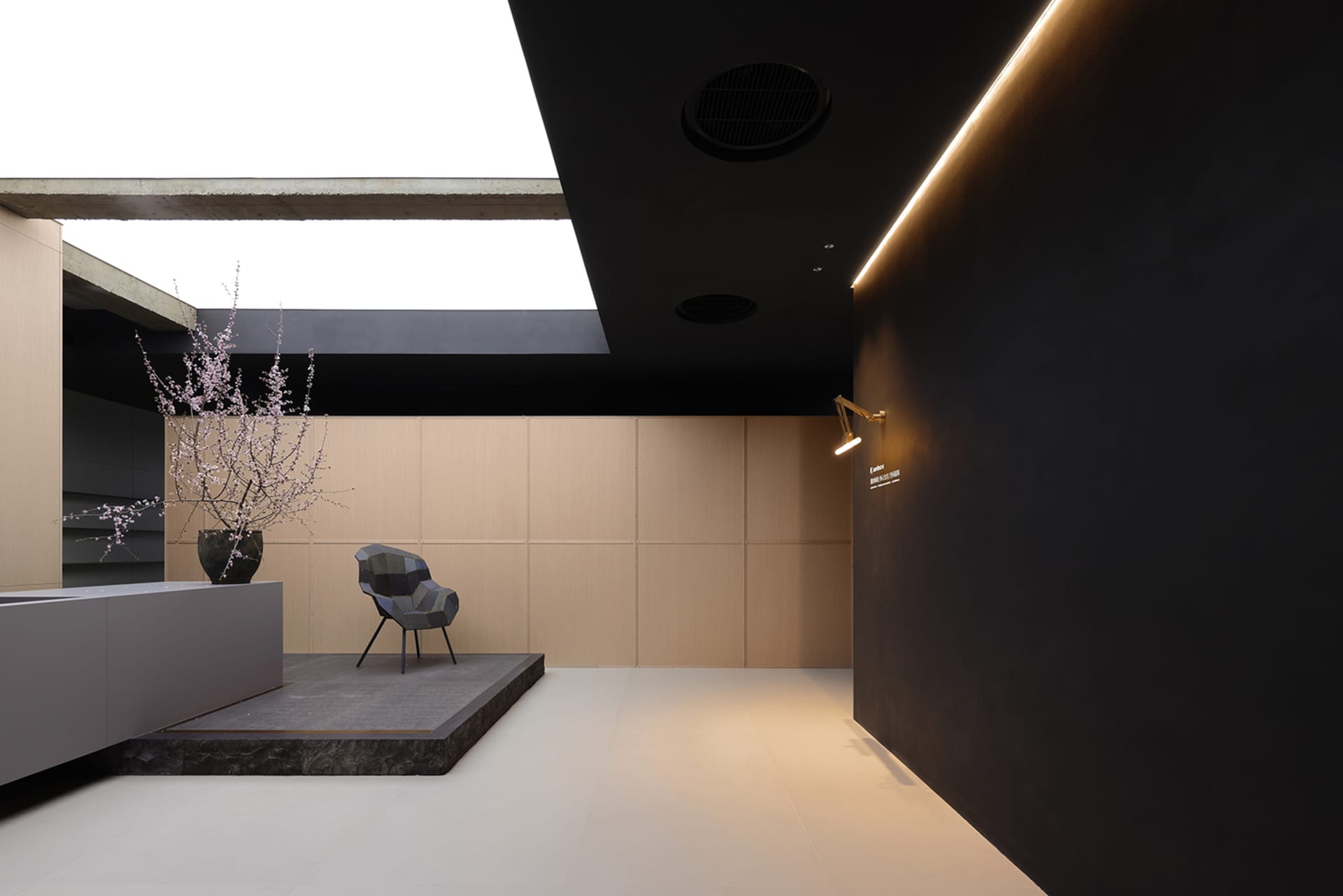 A minimalist office lobby with black walls, a concrete floor, and white ceiling.