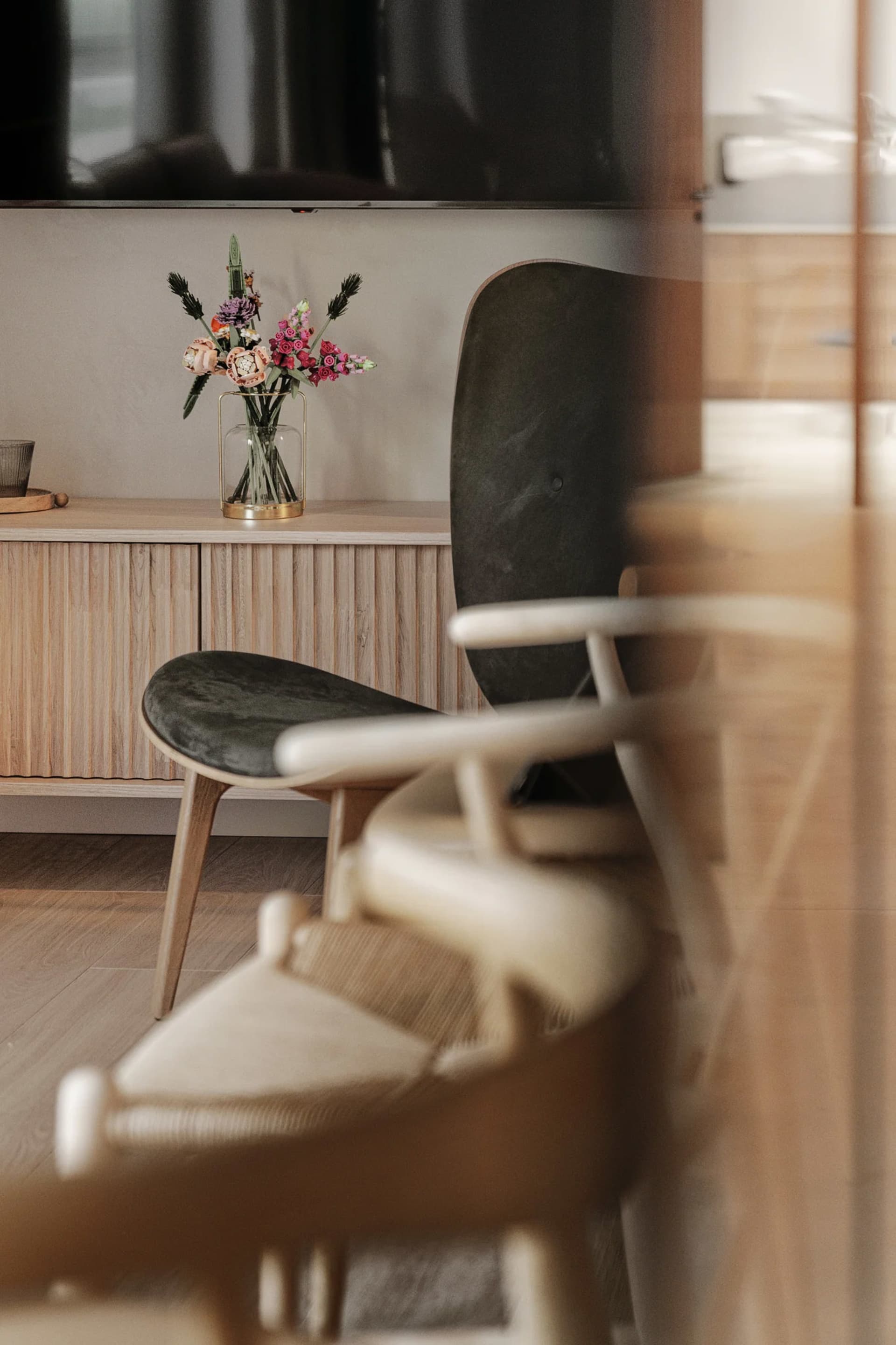 Minimalist living room with wooden furniture and a vase of flowers.