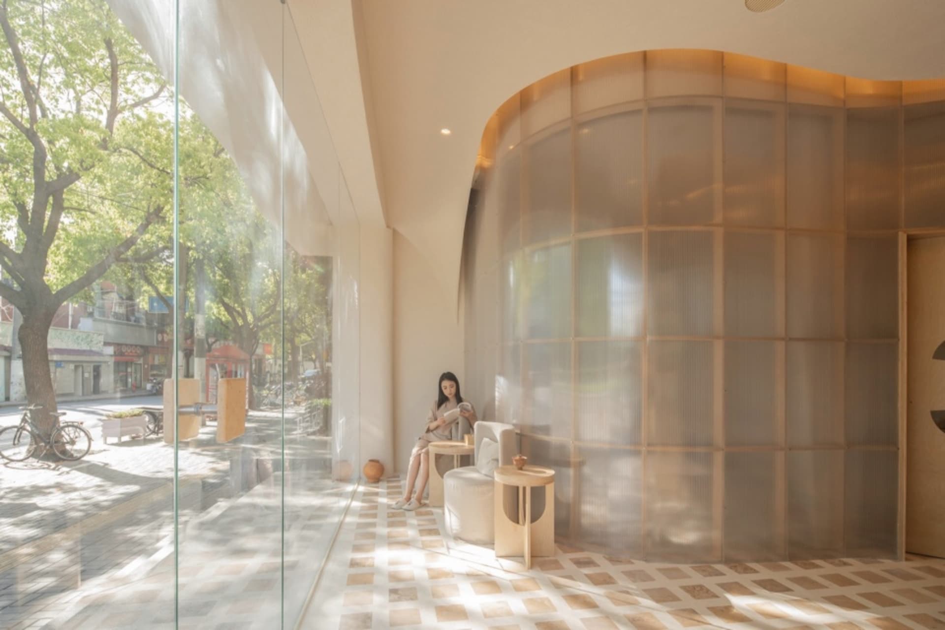 A minimalist interior design featuring glass walls and wooden furniture against a beige background.