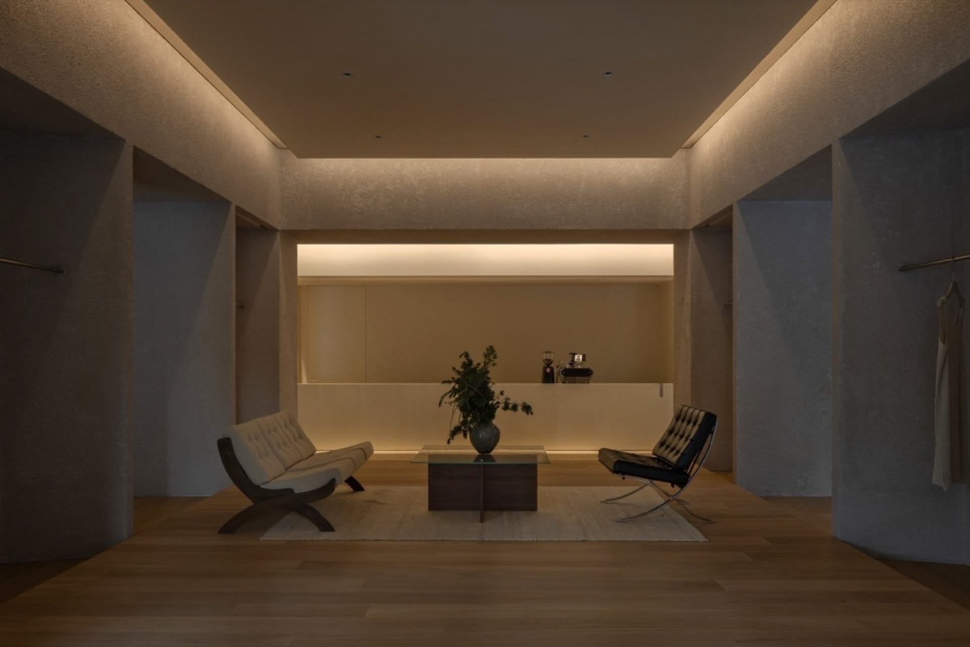 A modern living room with wooden and concrete surfaces featuring two armchairs and a coffee table with a plant.
