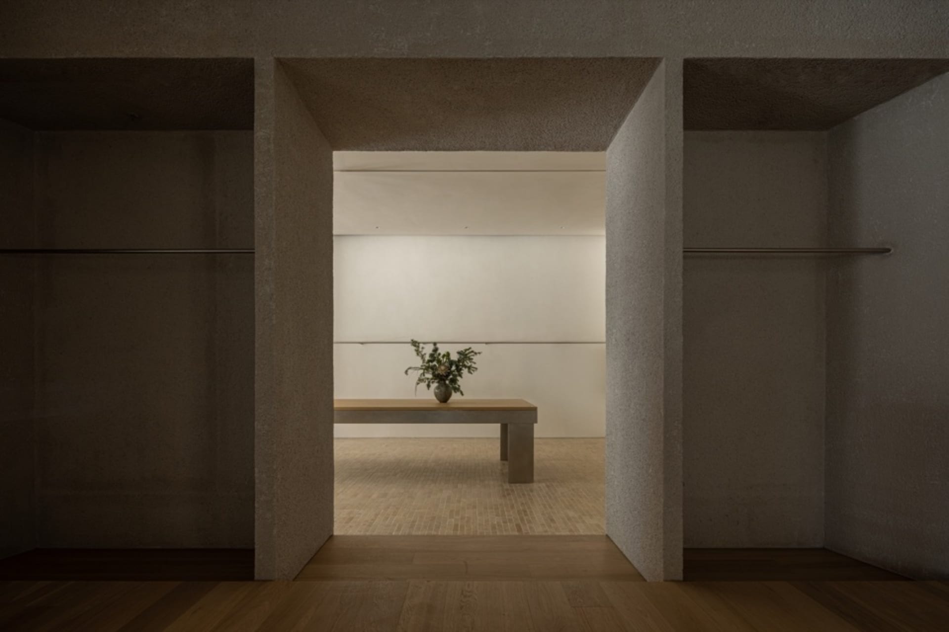A minimalist closet interior with a concrete bench and floral arrangement.