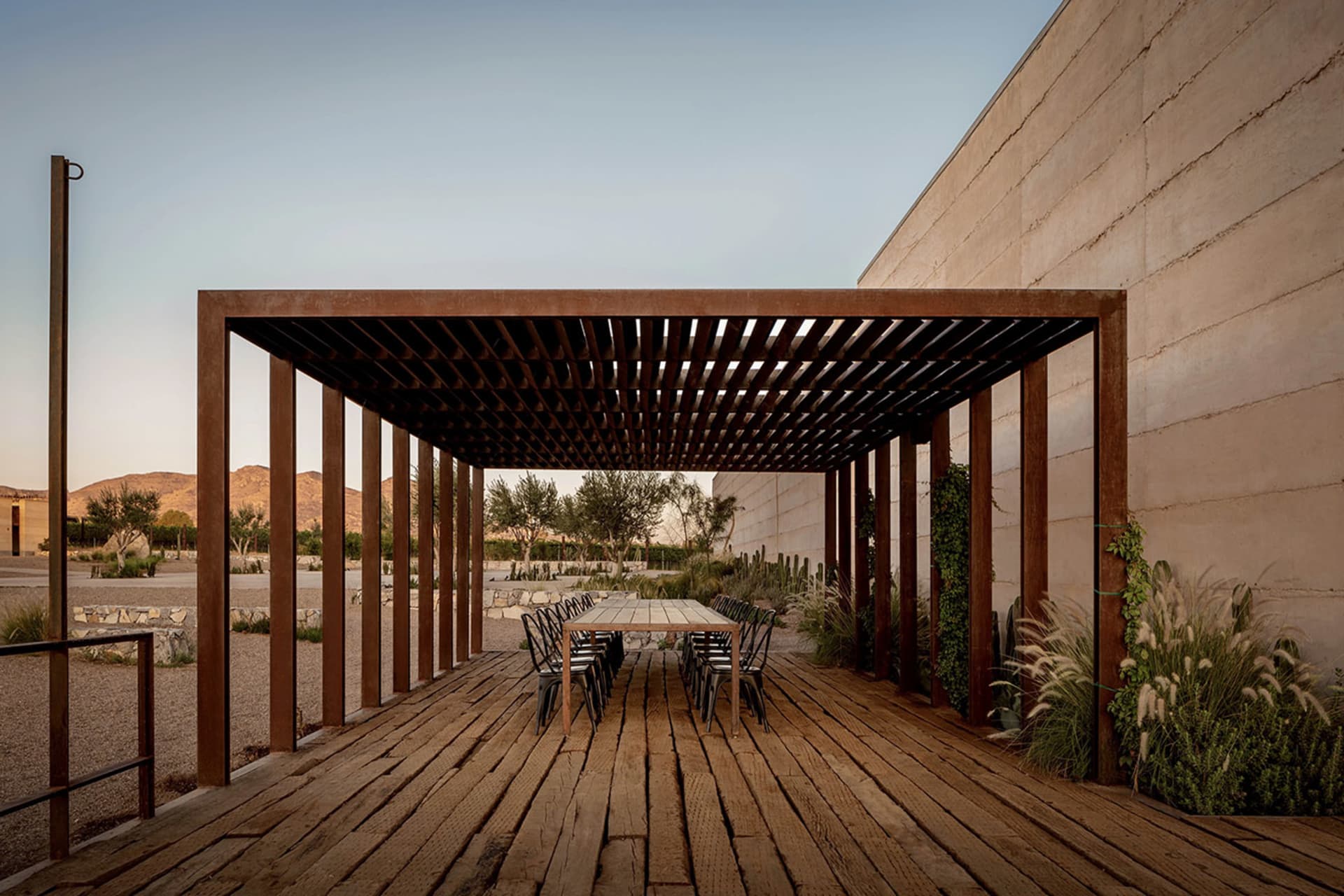 A modern patio area with wooden flooring, a wooden pergola, and seating for eight people.