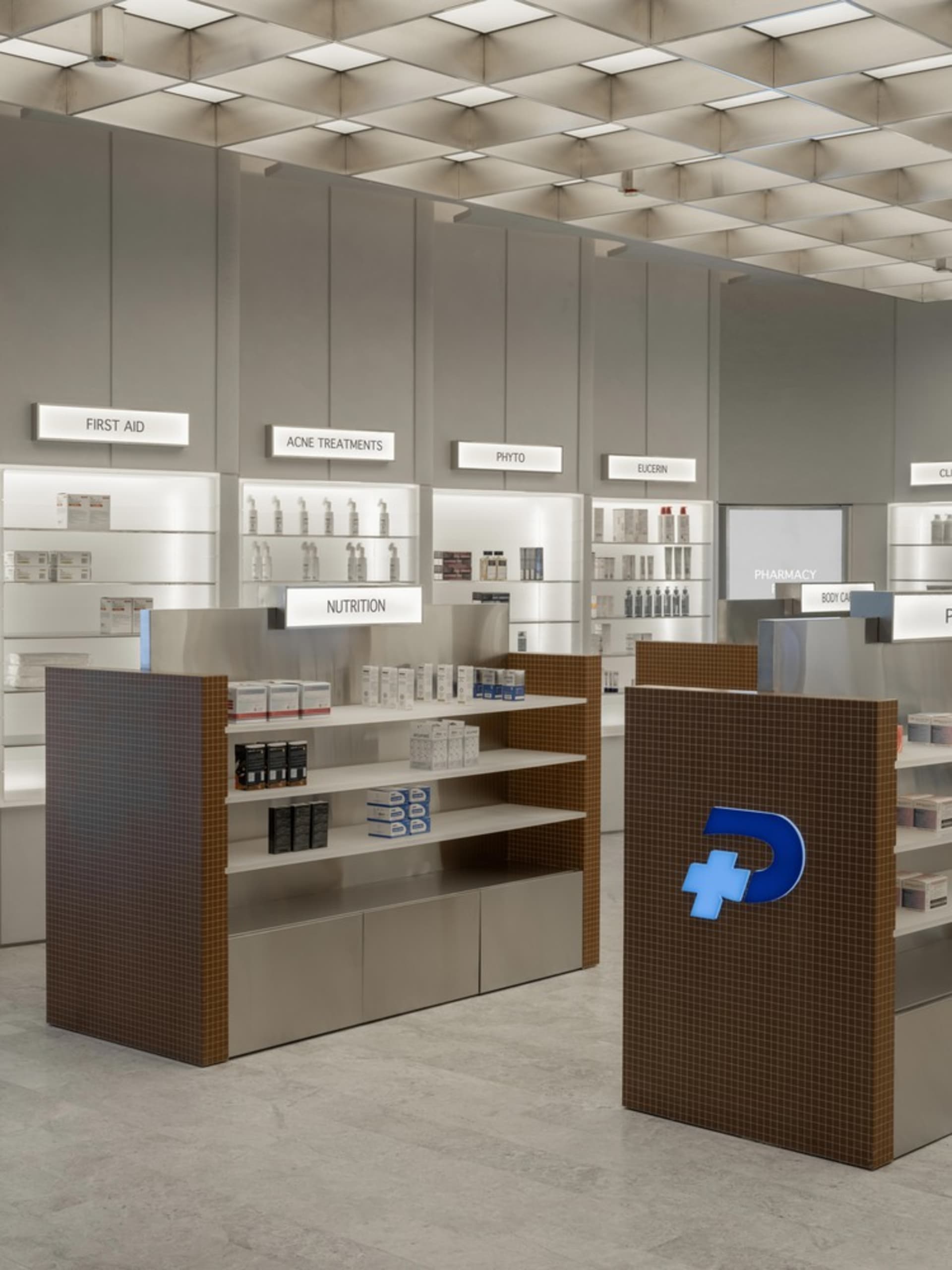A modern retail store featuring steel and glass elements, with shelves displaying products and a logo on the counter.
